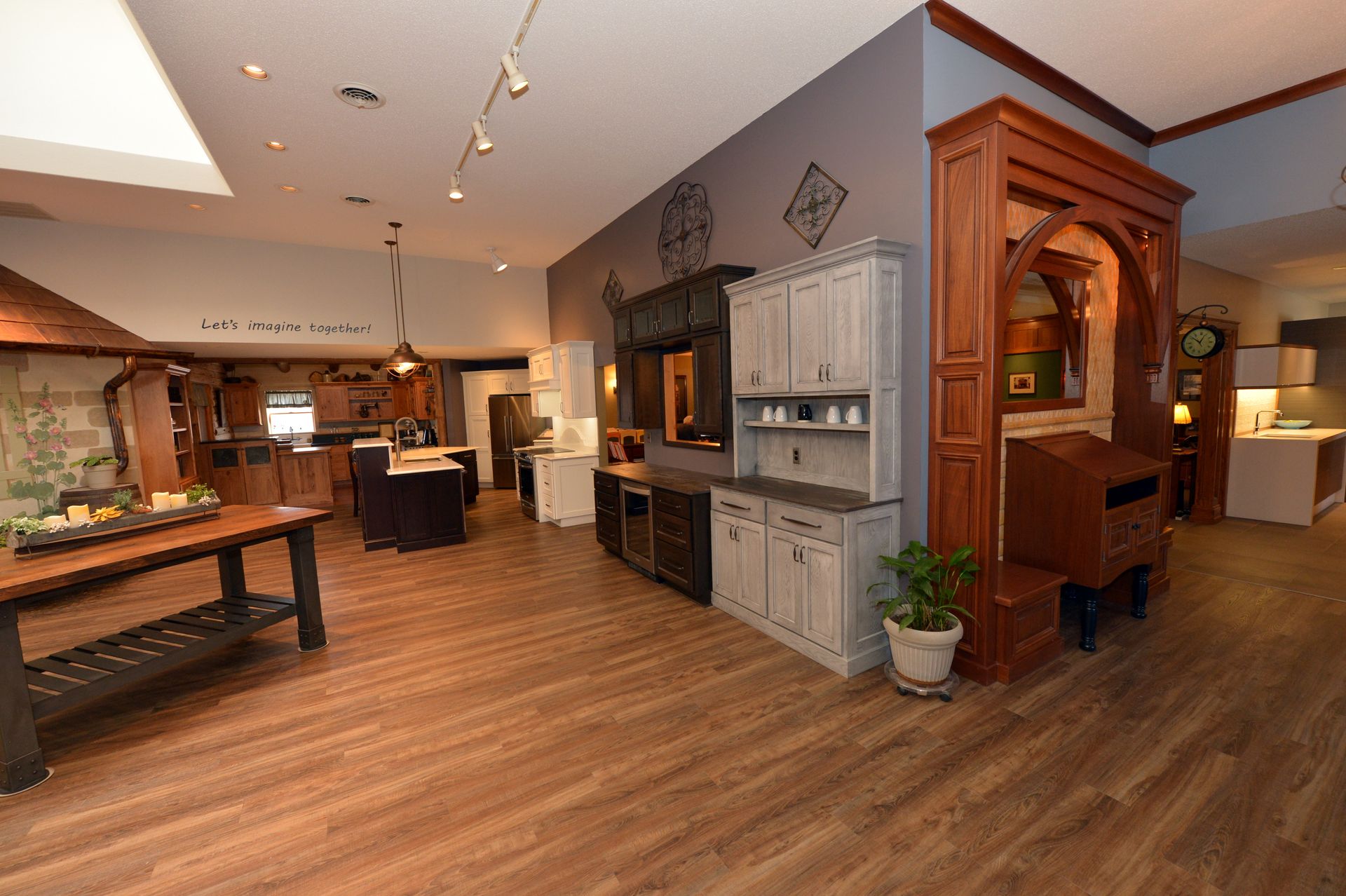 Spacious rustic kitchen with wooden floors, gray cabinets, a large island, and a wood hutch divider