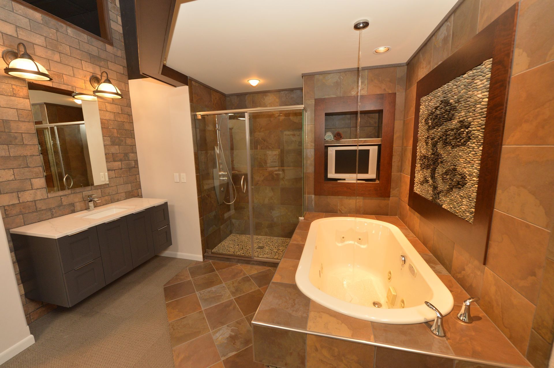 Modern bathroom with a freestanding tub, glass shower, double vanity, and warm brown tile finish