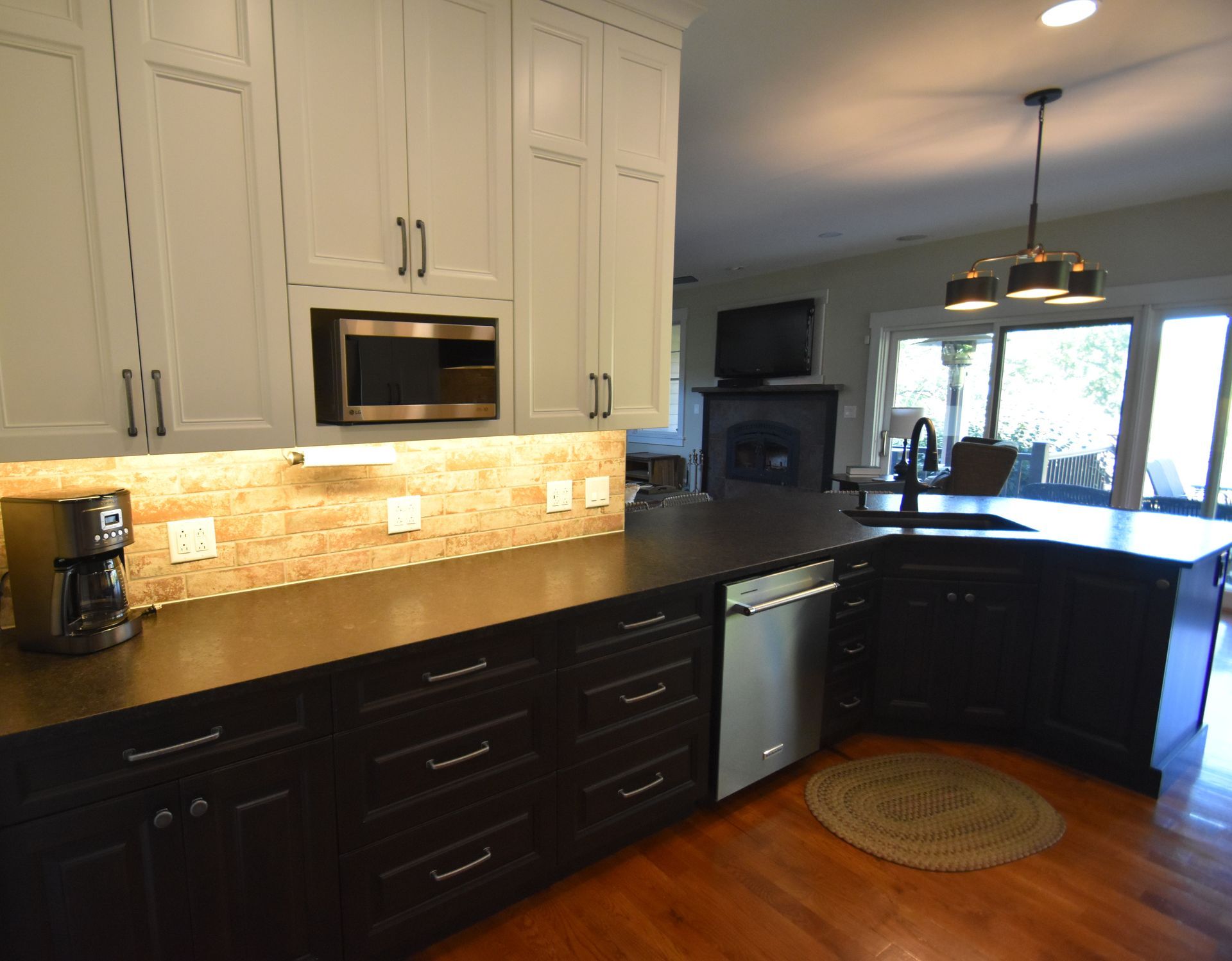 Modern kitchen with white and dark cabinets, stainless appliances, granite counters, and hardwood floors.