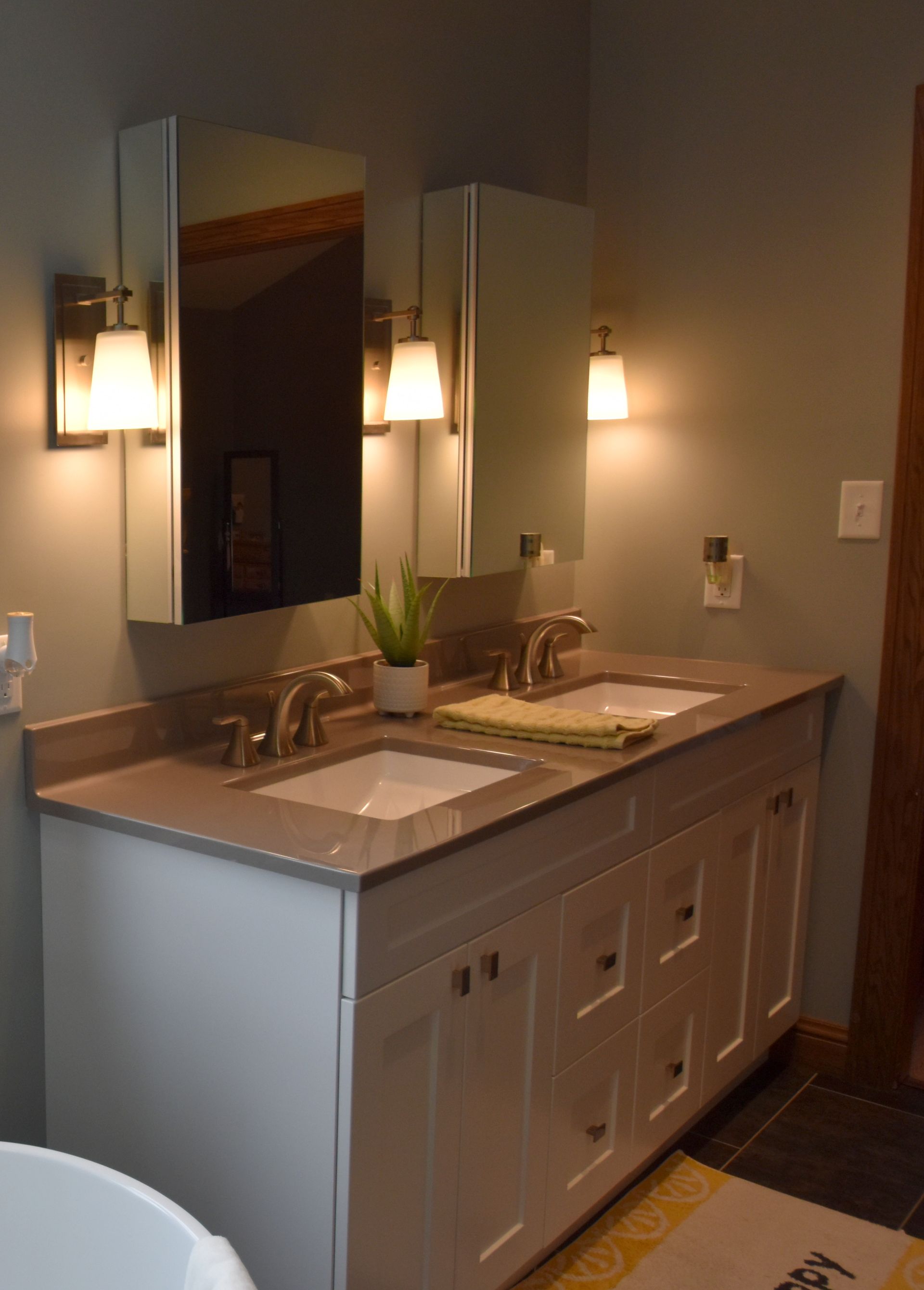 Modern bathroom vanity with double sinks, mirrors, and wall sconces in a gray-toned interior
