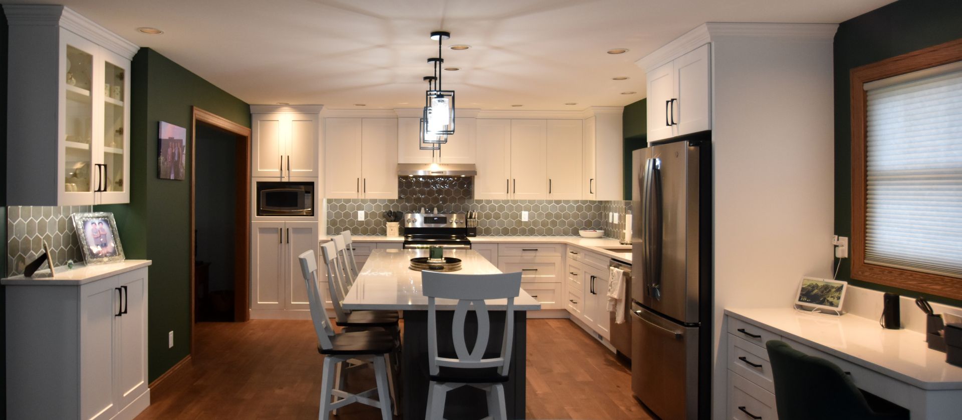 Modern kitchen with island, stainless appliances, white cabinets, and warm lighting