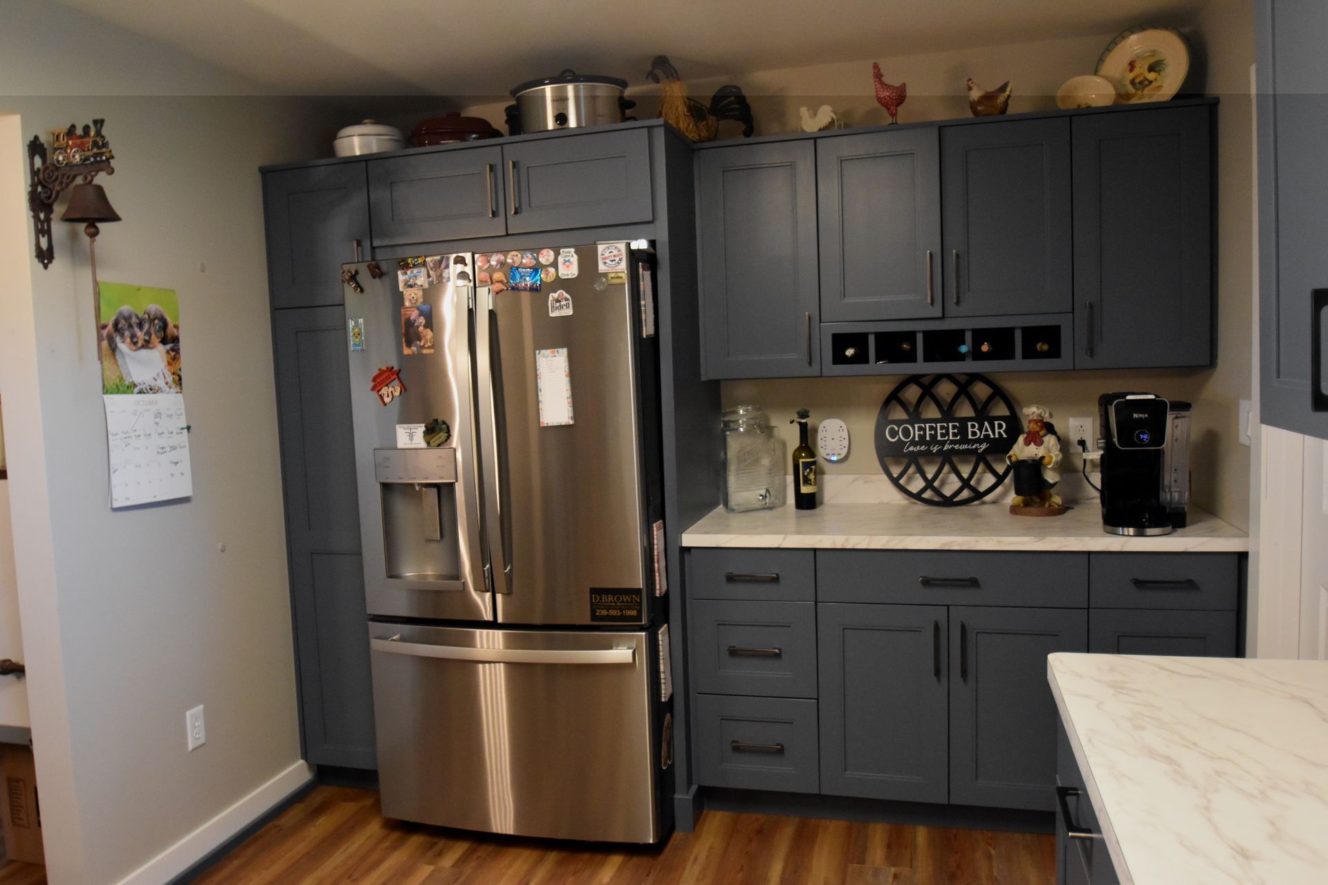 Modern kitchen with stainless steel refrigerator, blue-gray cabinets, and a light countertop