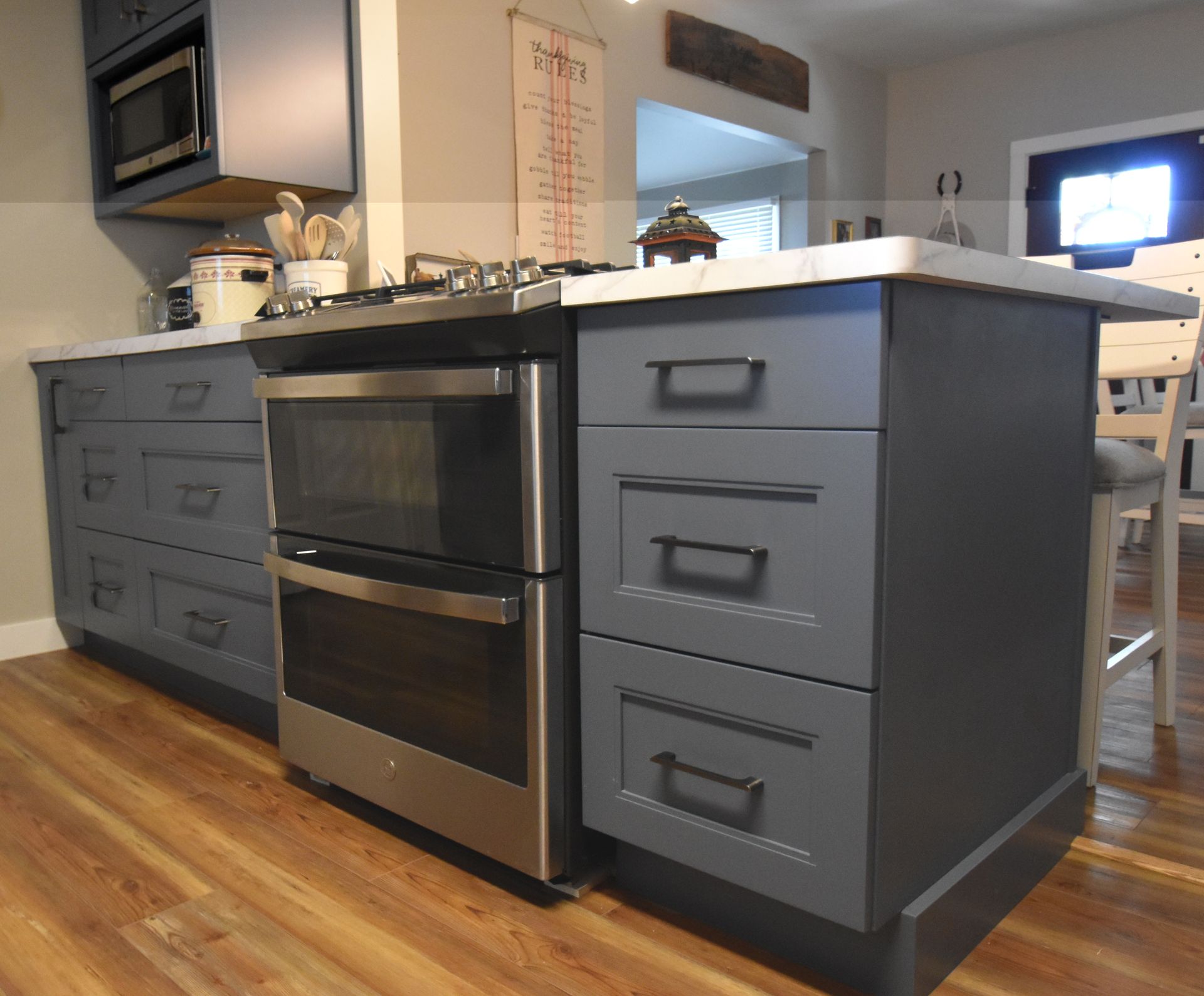 Kitchen island with gray cabinets and stainless oven in a modern kitchen