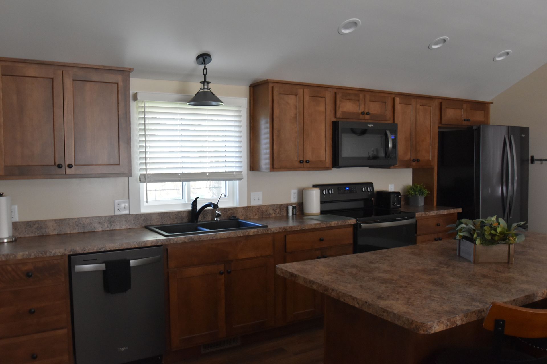 Modern kitchen with wood cabinets, black appliances, granite counters, and a central island