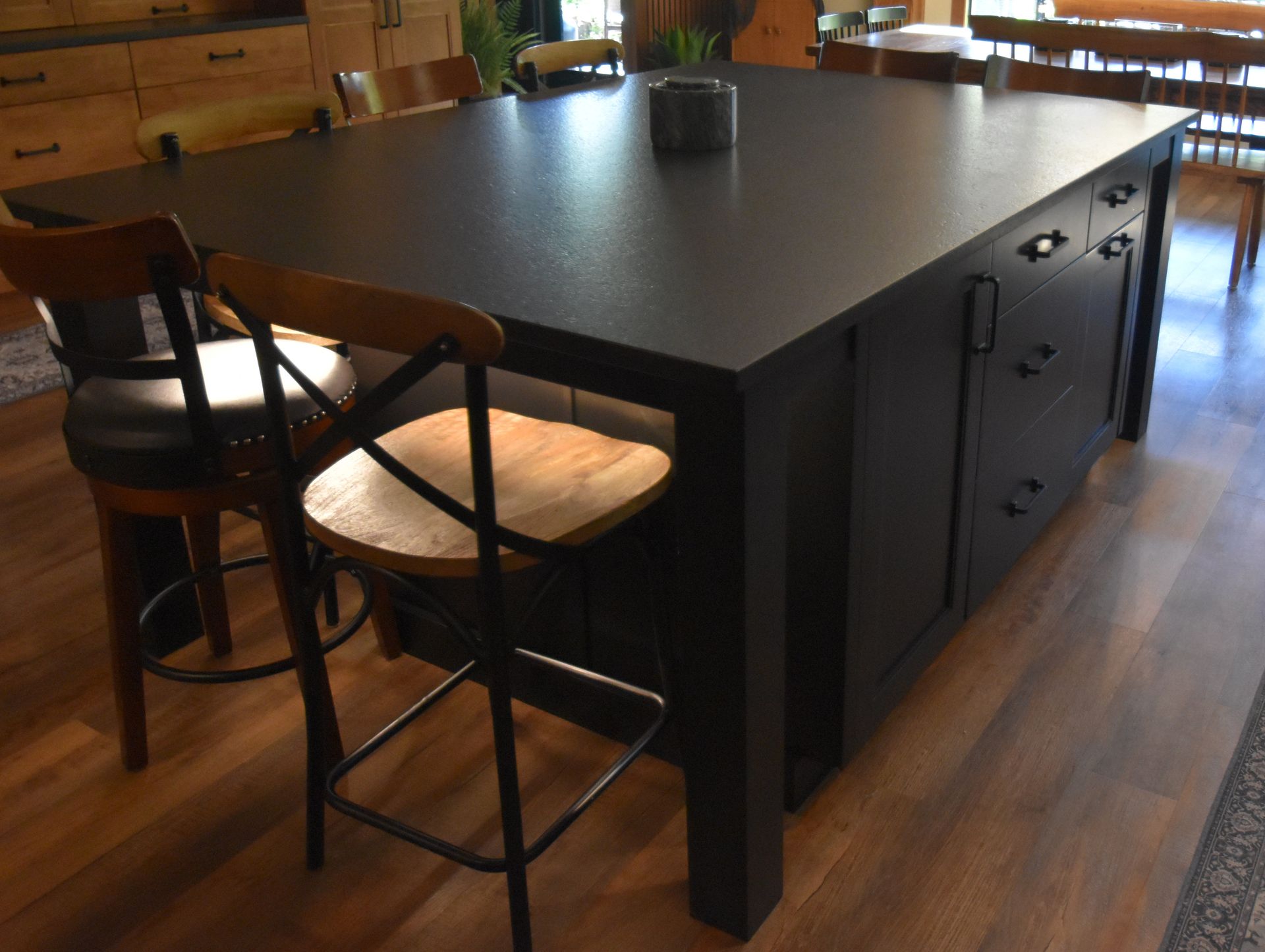 Large black kitchen island with bar stools in a modern wooden-floored kitchen