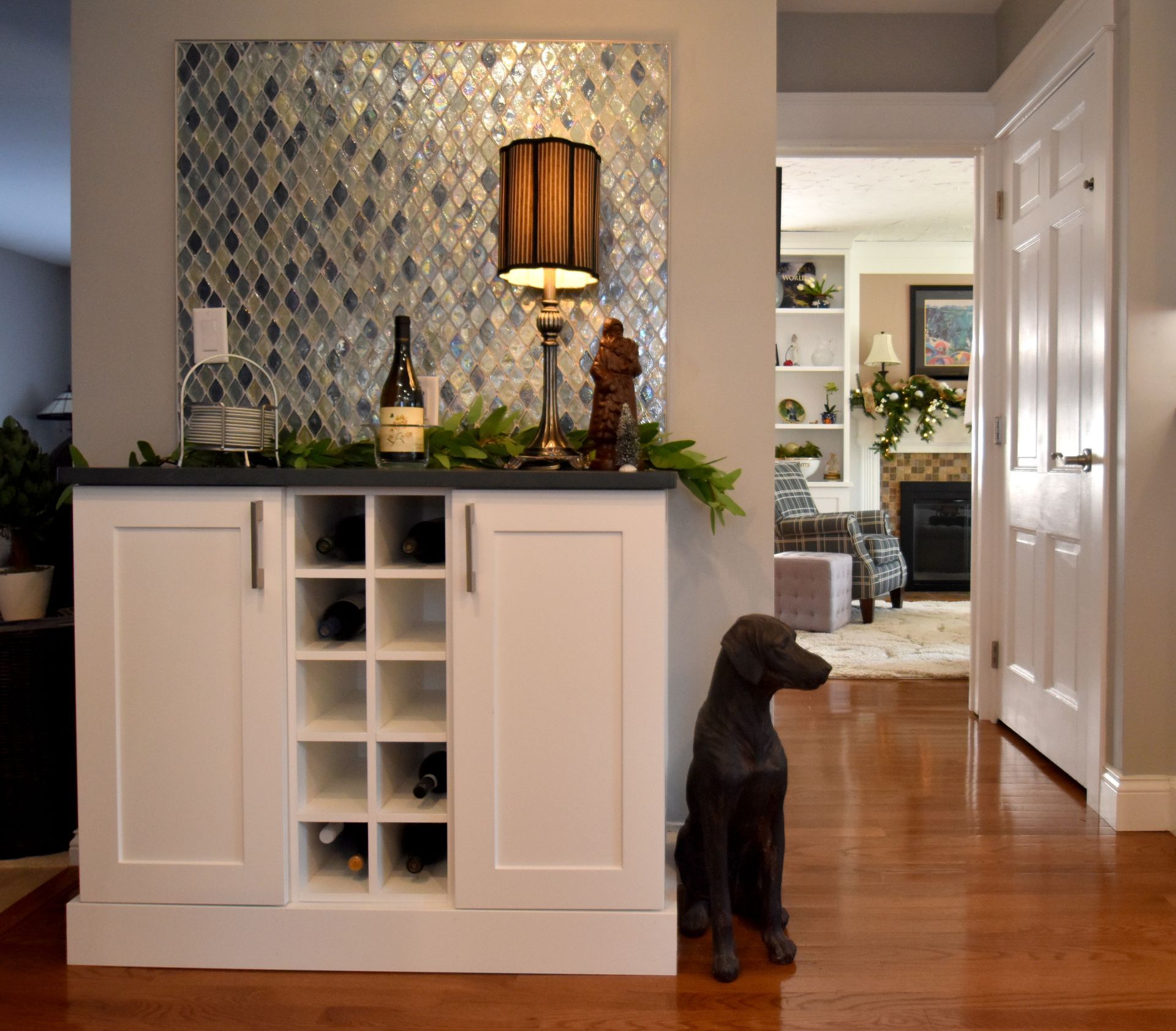 Living room console with lamp and decor; a small brown dog sits on the hardwood floor nearby.