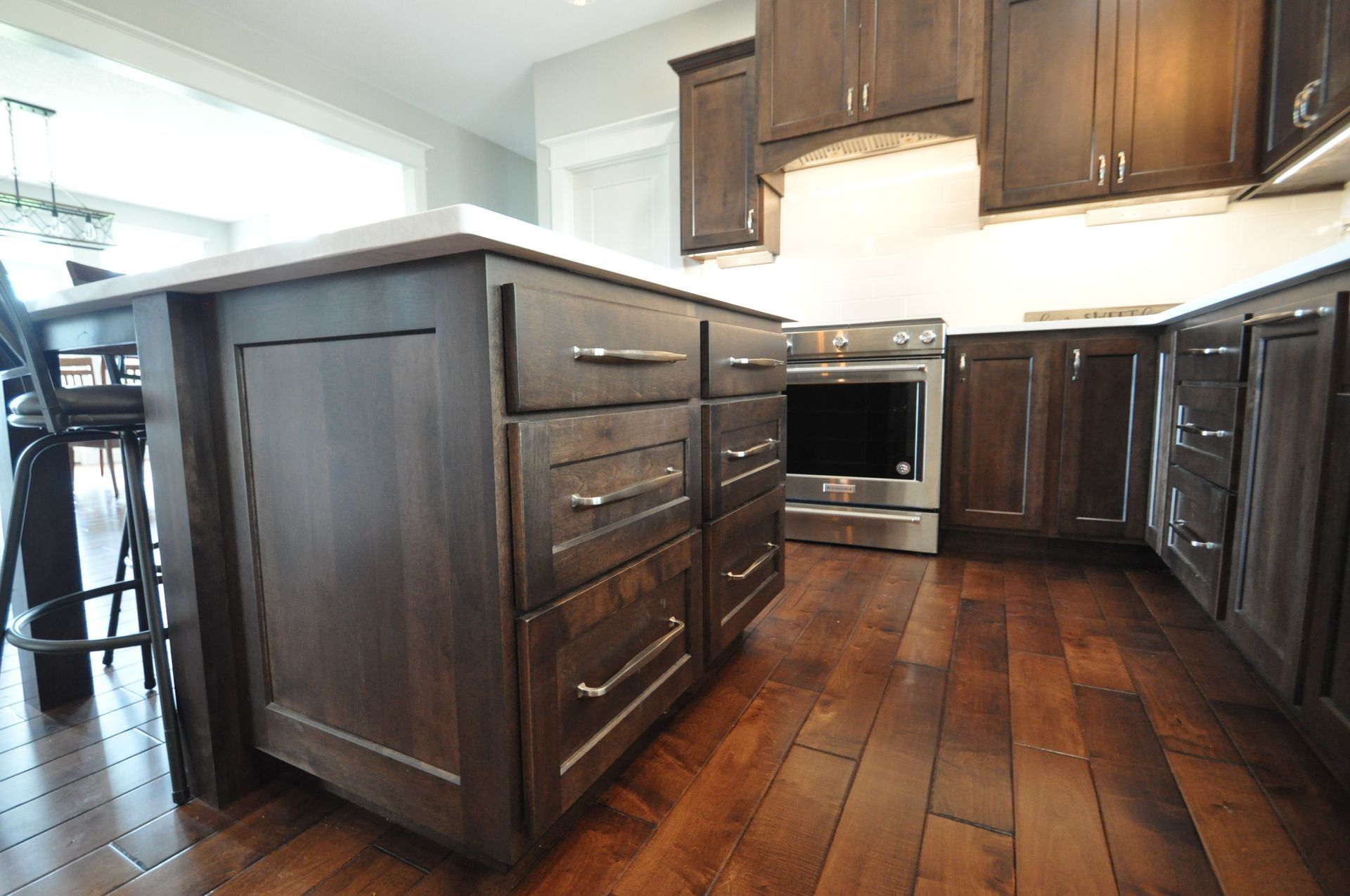 Modern kitchen with dark wood cabinets, island, stainless oven, and hardwood floors