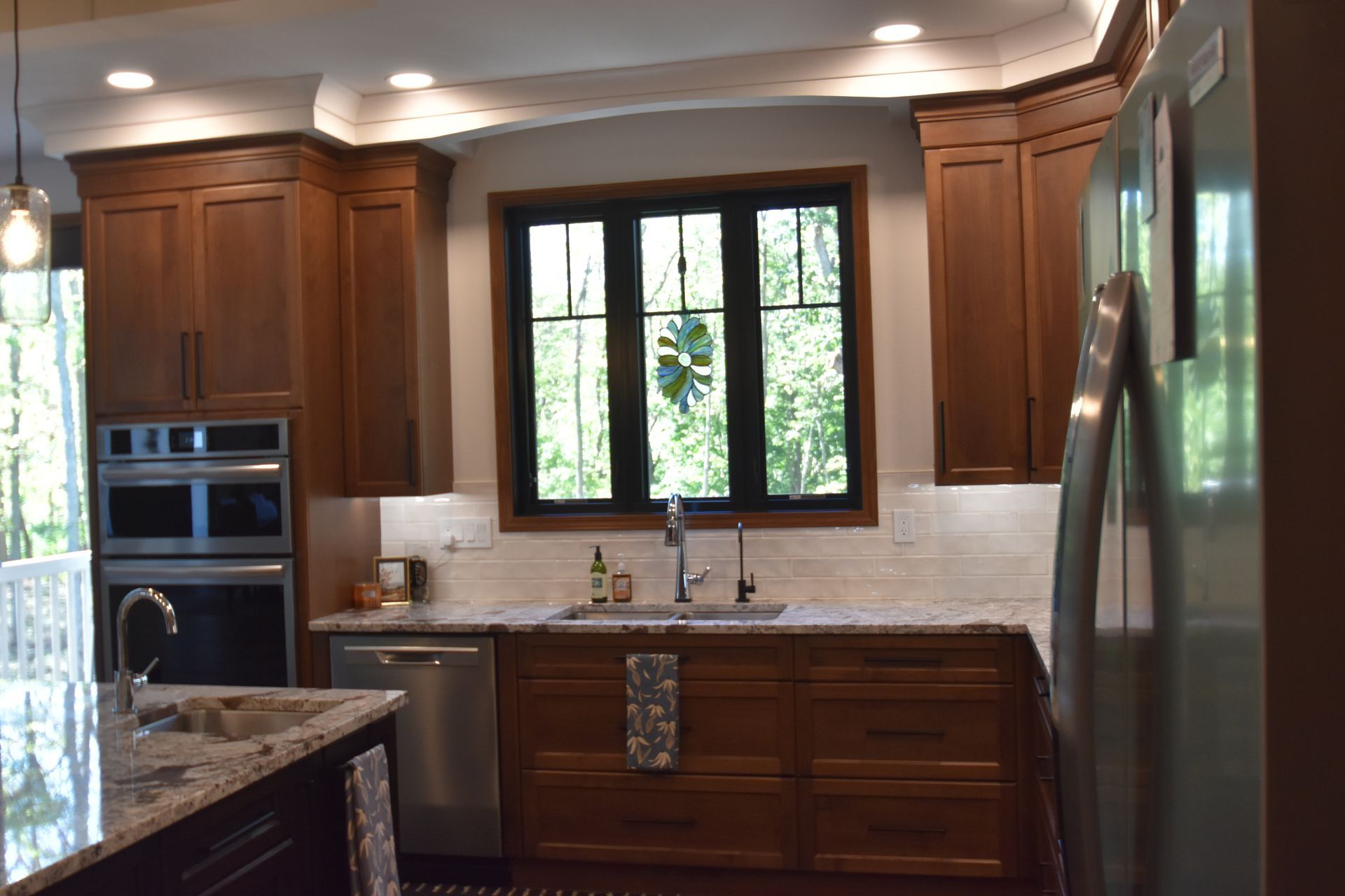 Modern kitchen with dark wood cabinets, granite counters, white backsplash, and a window above the sink.