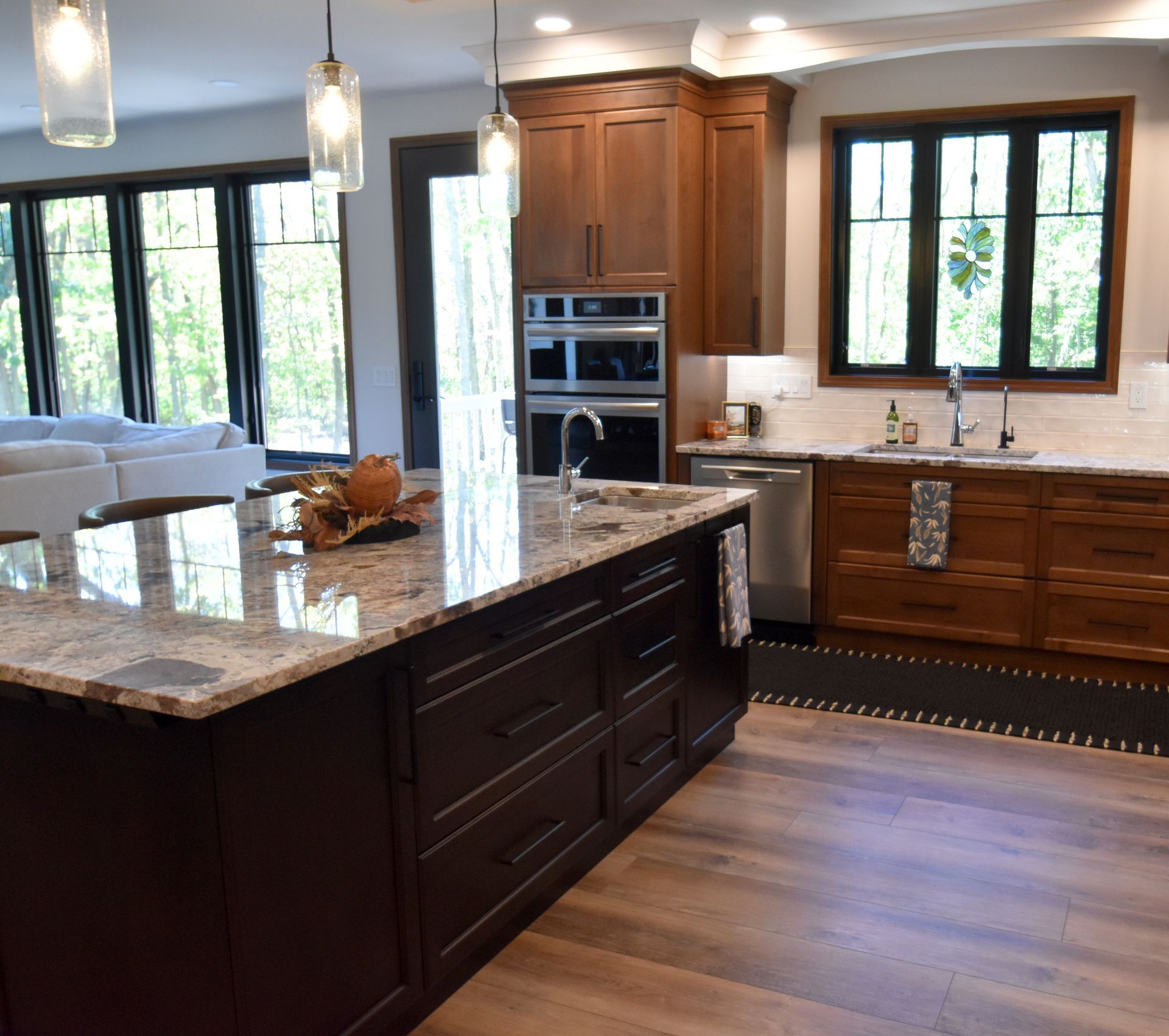 Modern kitchen with dark island, granite countertops, wood cabinets, and large windows
