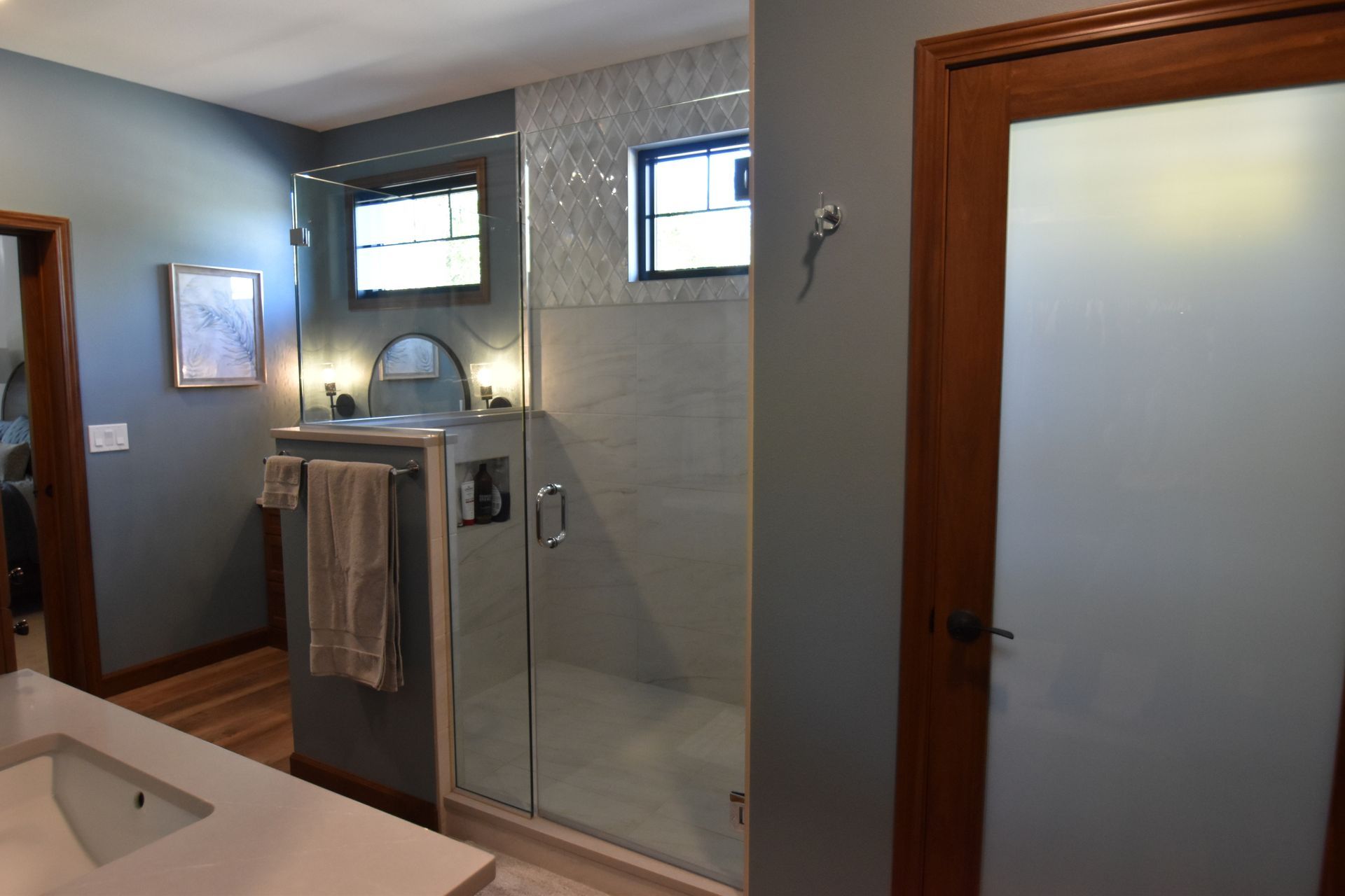 Modern bathroom with a glass shower enclosure, frosted door, and small windows above the tiled wall.