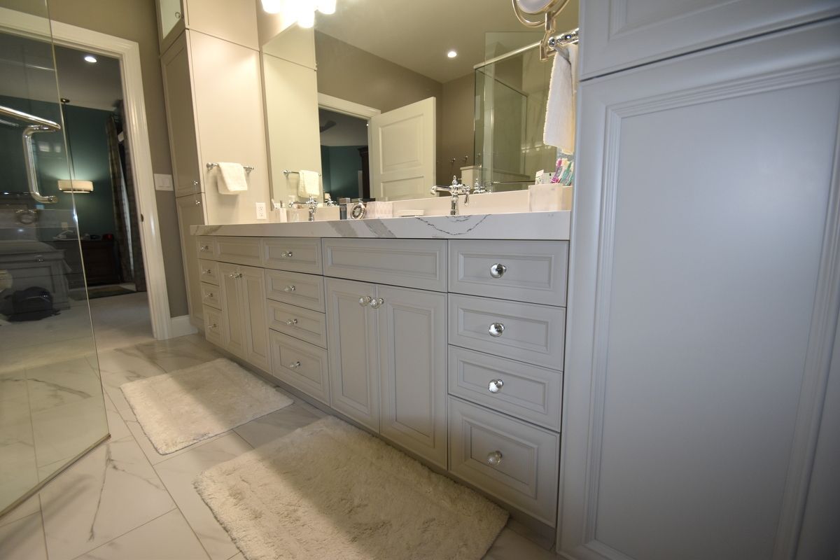 White bathroom vanity with double sinks, large mirror, and marble tile floor.