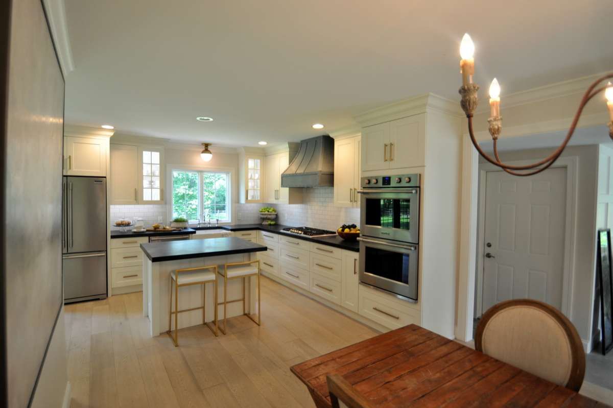 Bright modern kitchen with white cabinets, island, stainless appliances, and a dining table in the foreground