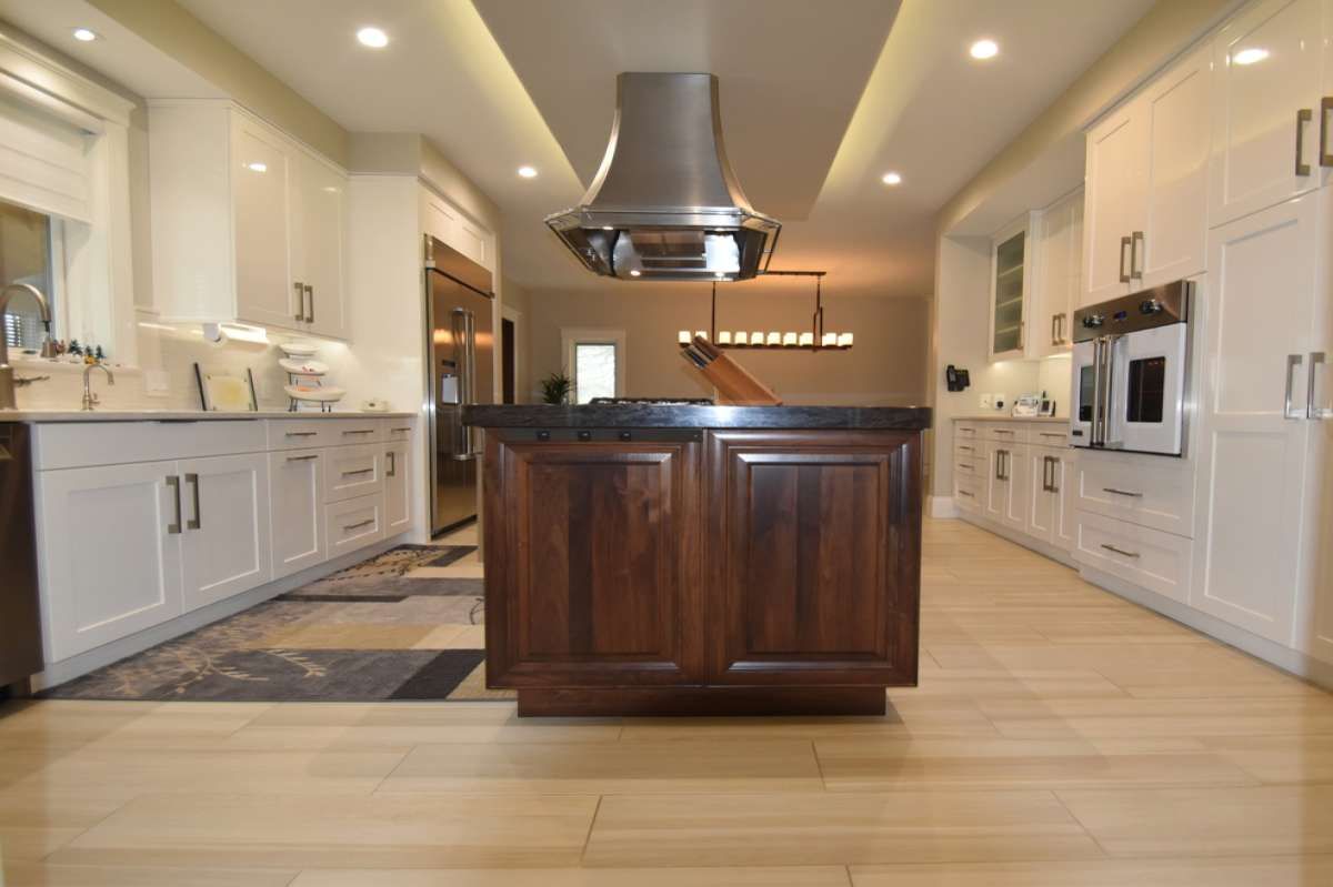 Modern kitchen with white cabinets, a dark wood island, and stainless steel range hood