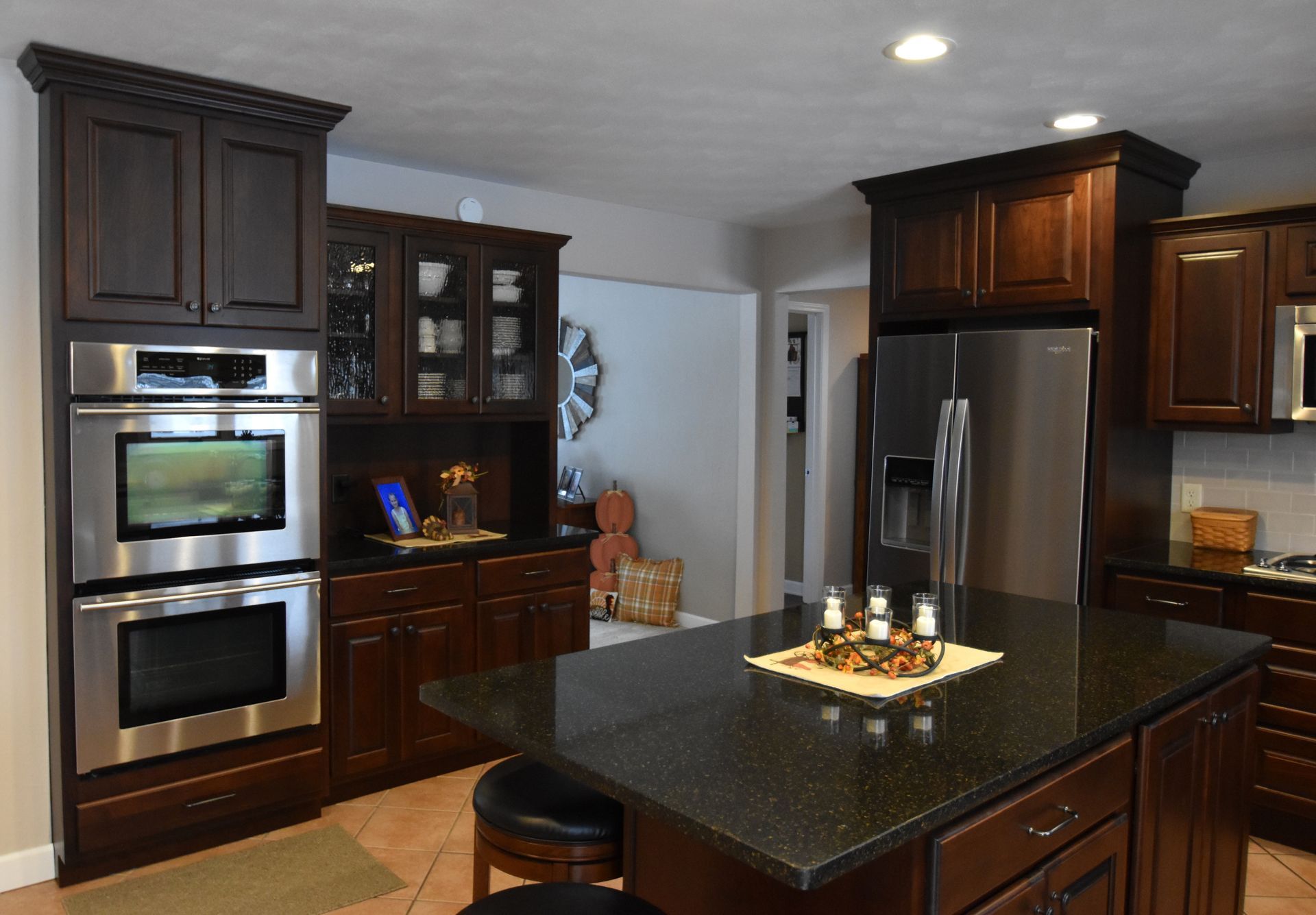 Modern kitchen with dark wood cabinets, stainless steel appliances, and a black granite island countertop