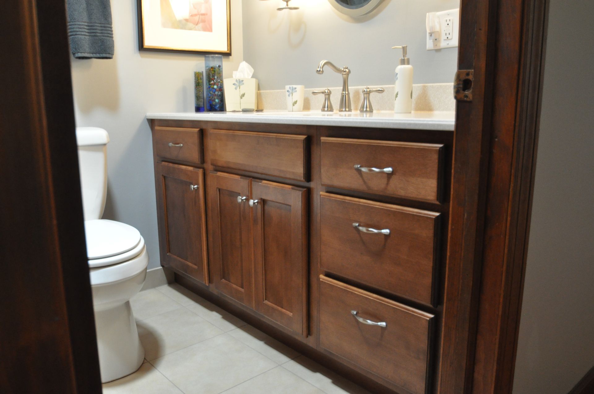 Bathroom vanity with dark wood cabinets, white countertop, sink, and toilet visible on the left