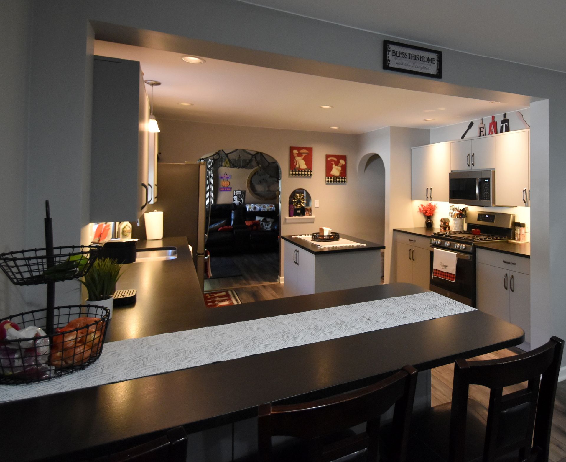 Open-concept kitchen and dining area with dark counters, white cabinets, and a bar overlooking the room.