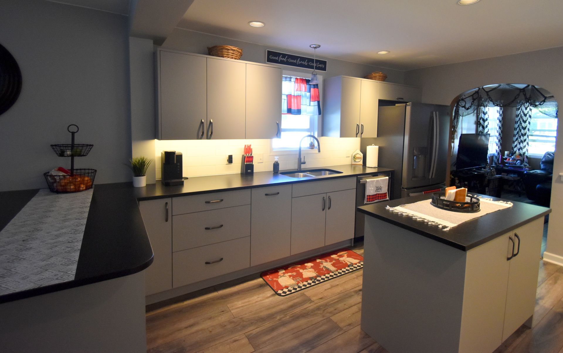 Modern kitchen with white cabinets, central island, stainless fridge, and daylight from a small window.