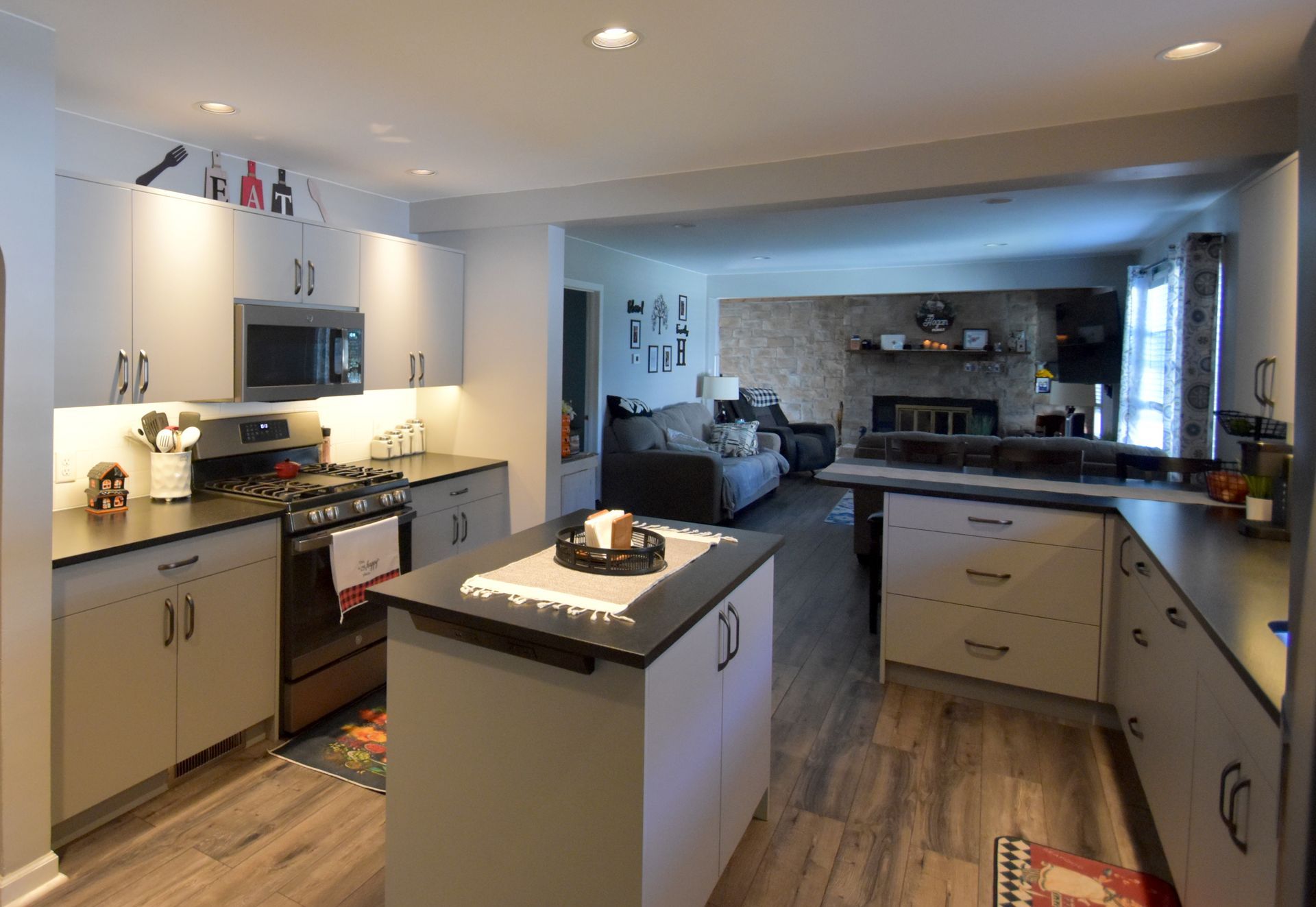 Modern kitchen with white cabinets, central island, stainless appliances, and wood floors