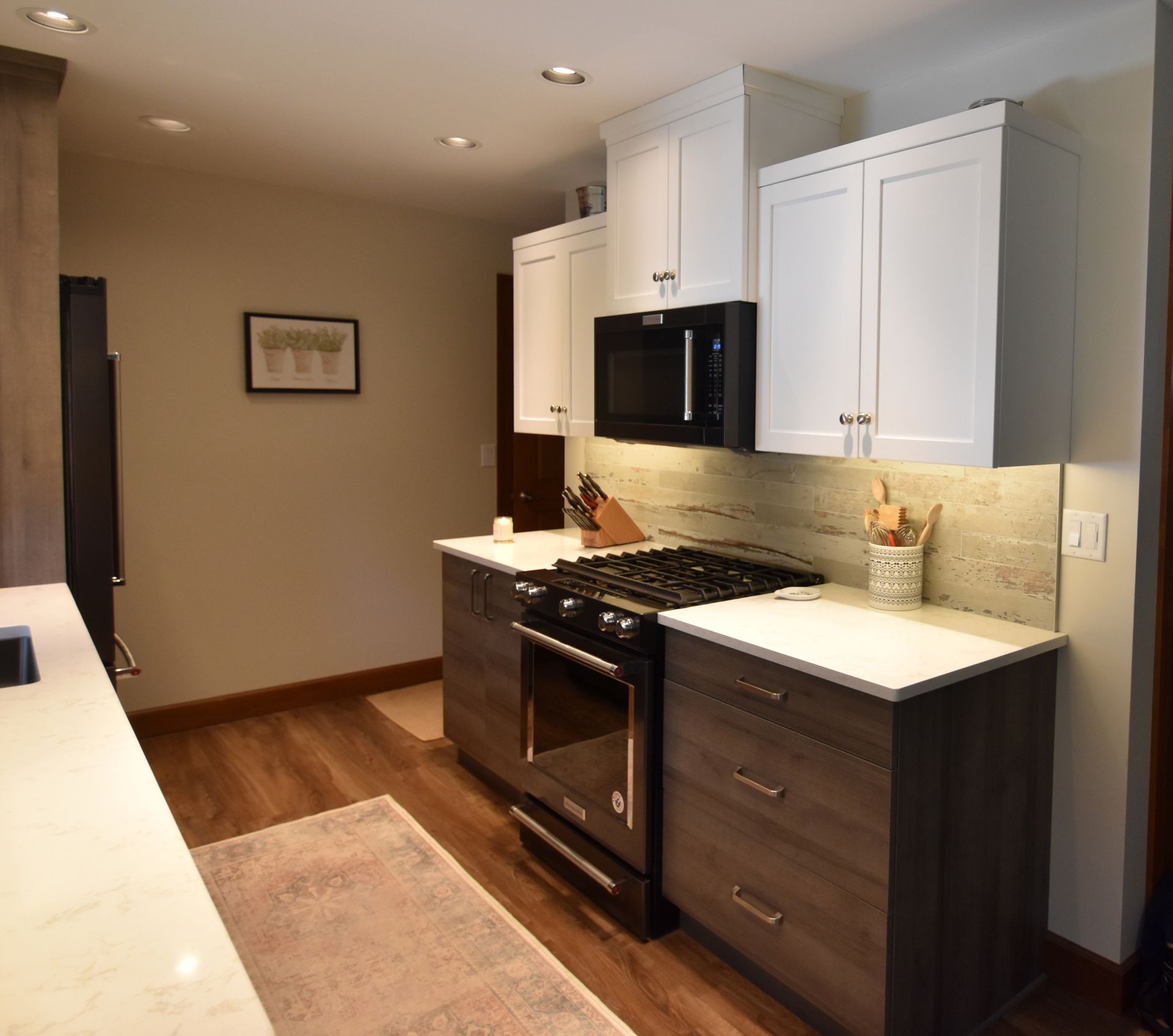 Modern kitchen with dark cabinets, white countertops, stainless stove, and wood flooring