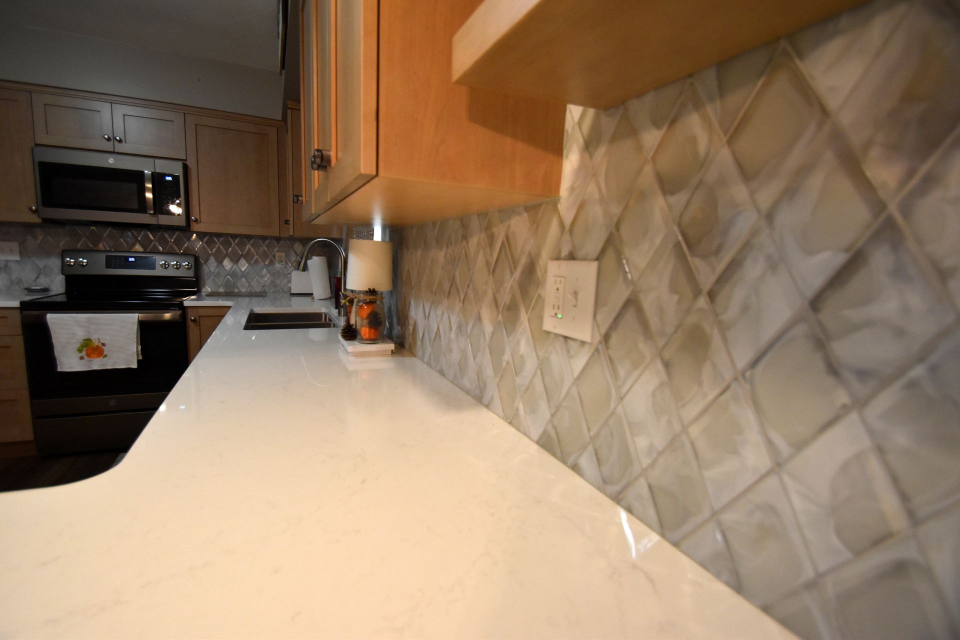 Modern kitchen countertop with tiled backsplash and stainless steel appliances in the background