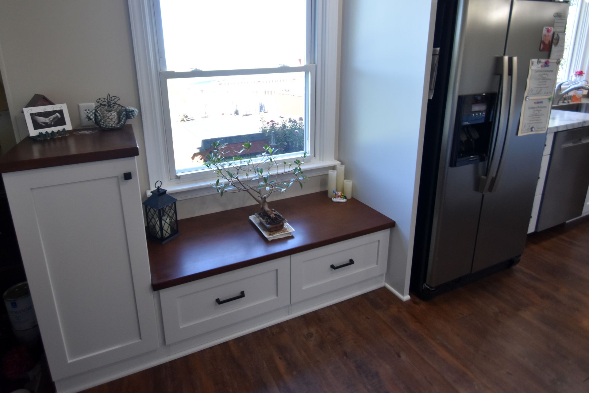 Kitchen window bench with drawers, potted plant, and stainless steel refrigerator