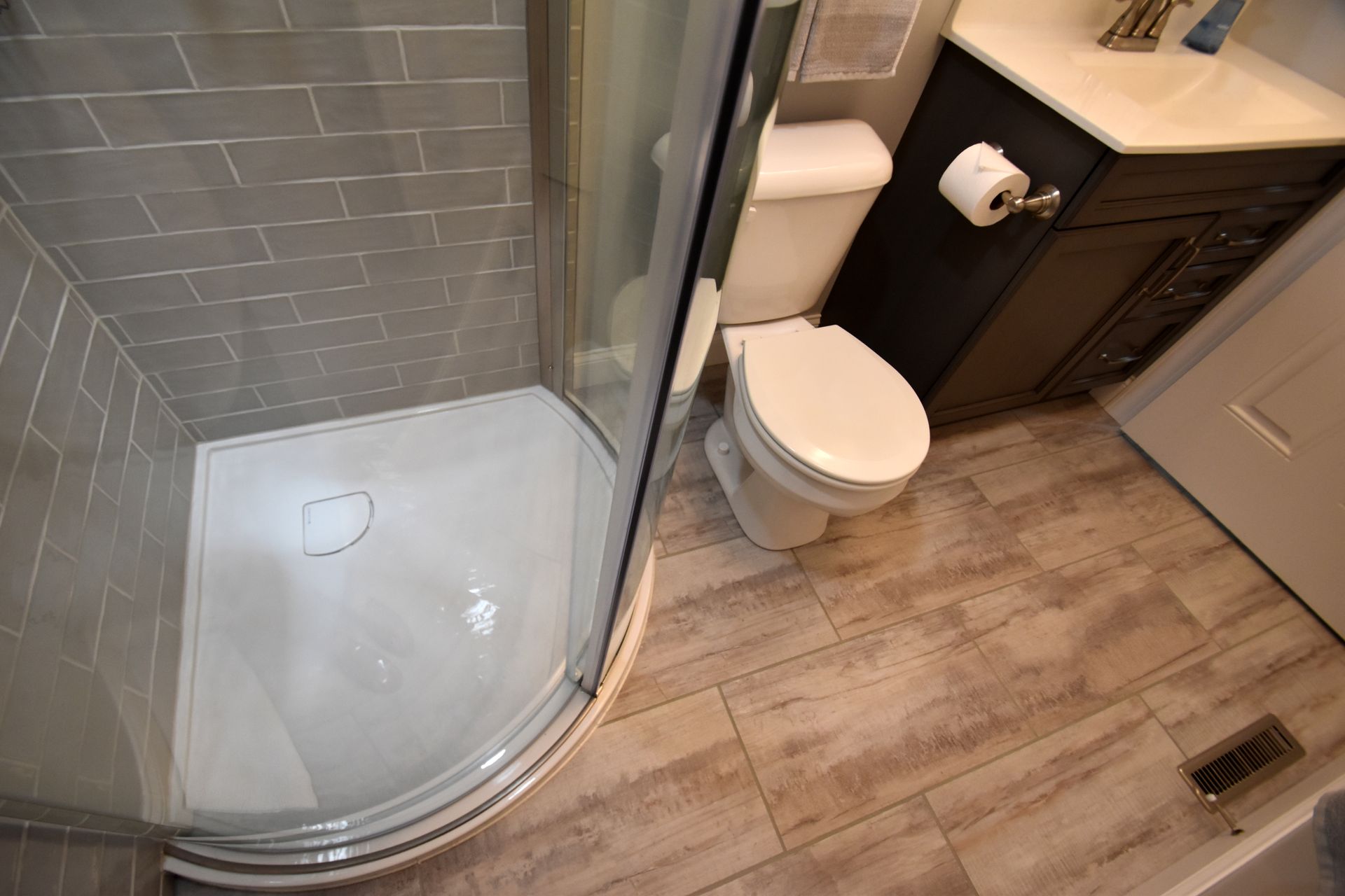 Bathroom with glass shower, toilet, and wood-look tile floor