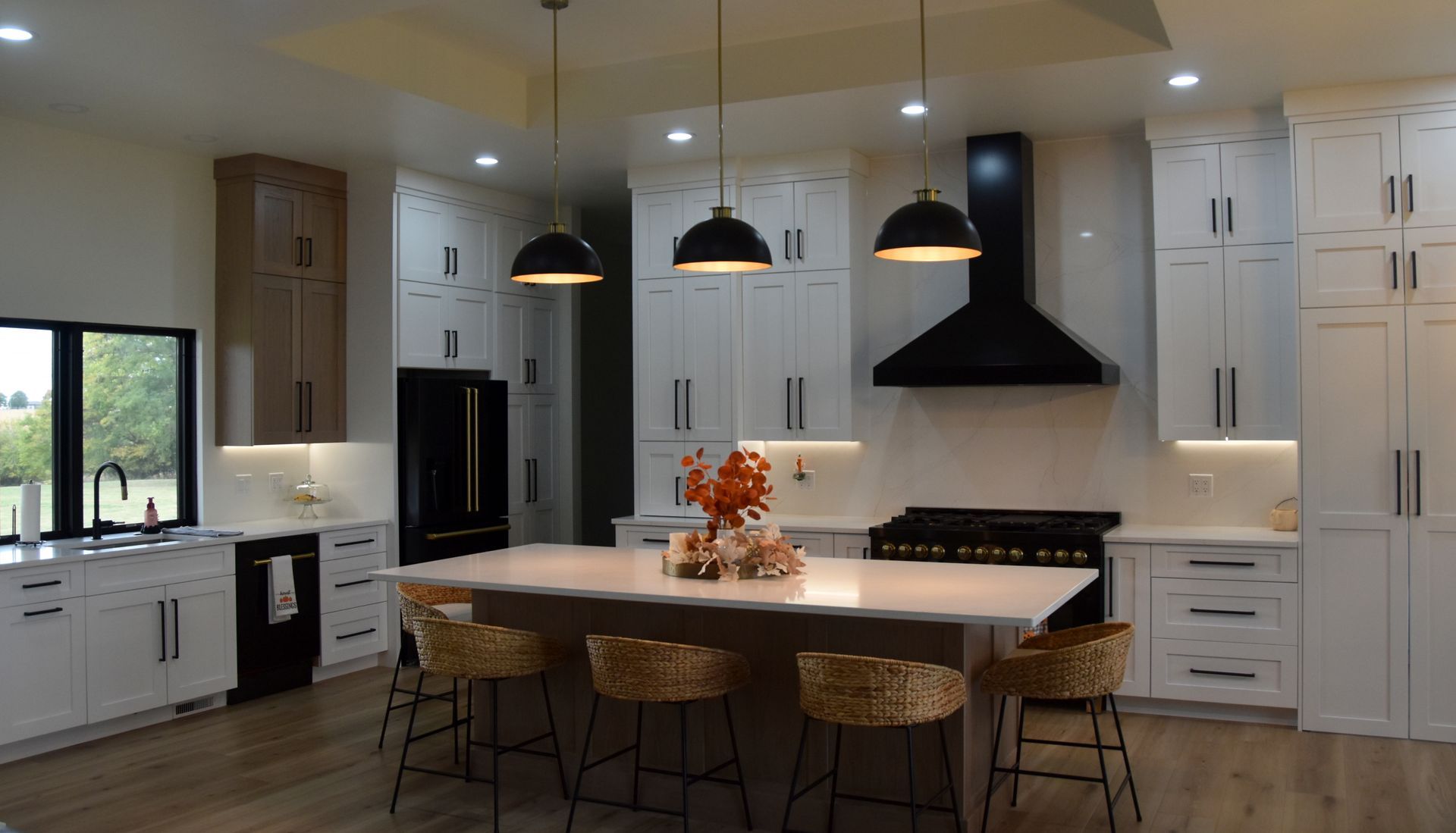 Bright modern kitchen with white cabinets, black range hood, and a large island with pendant lights