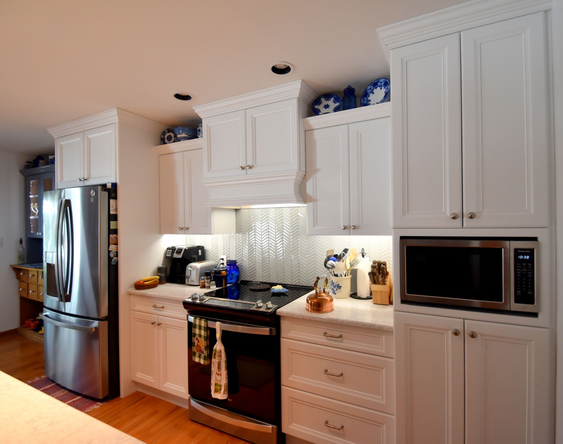 Bright modern kitchen with white cabinets, stainless fridge, and built-in microwave