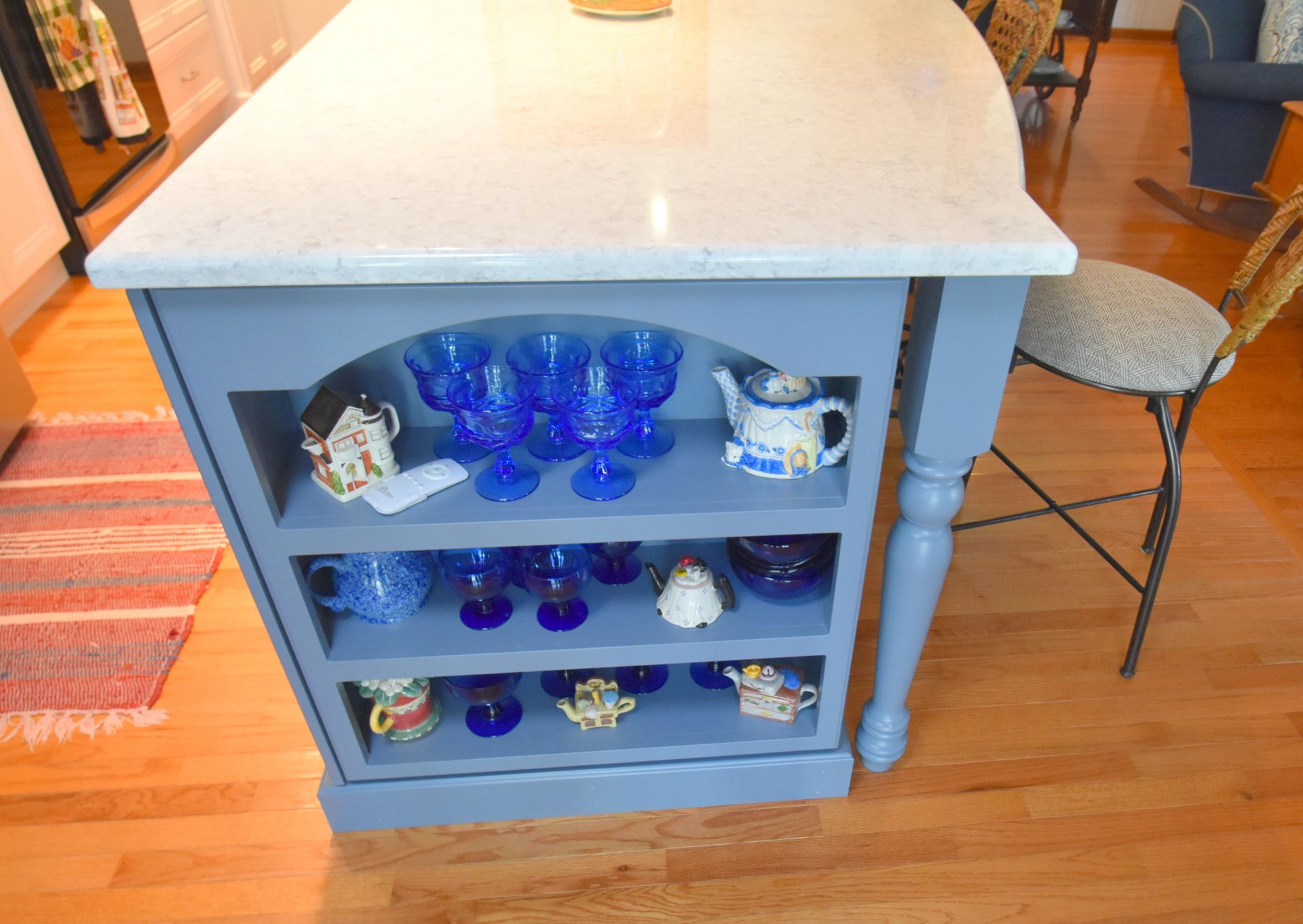 Blue glassware displayed on shelves beneath a kitchen island with a marble top
