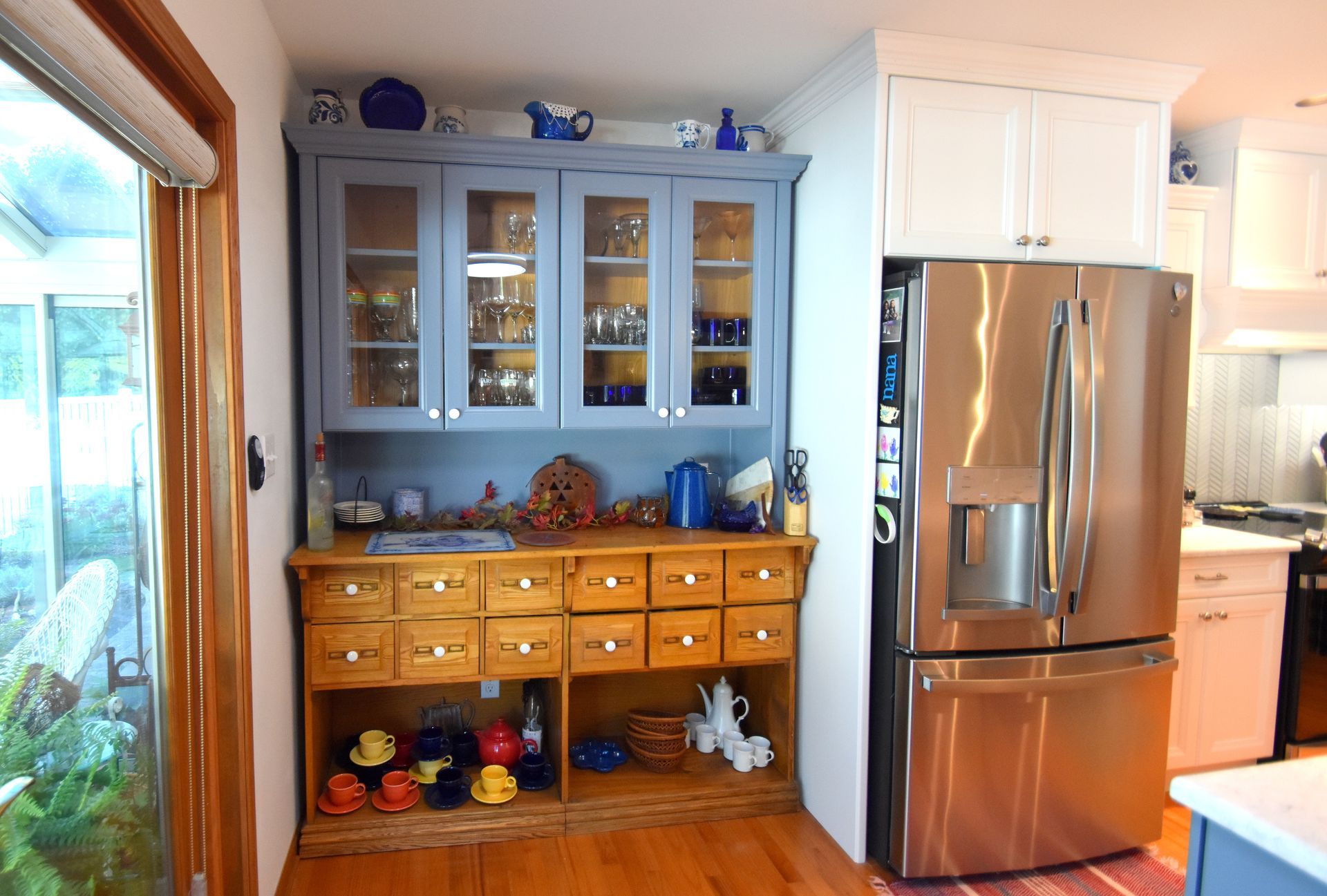 Kitchen with blue hutch, wooden cabinet, and stainless steel refrigerator beside a doorway.