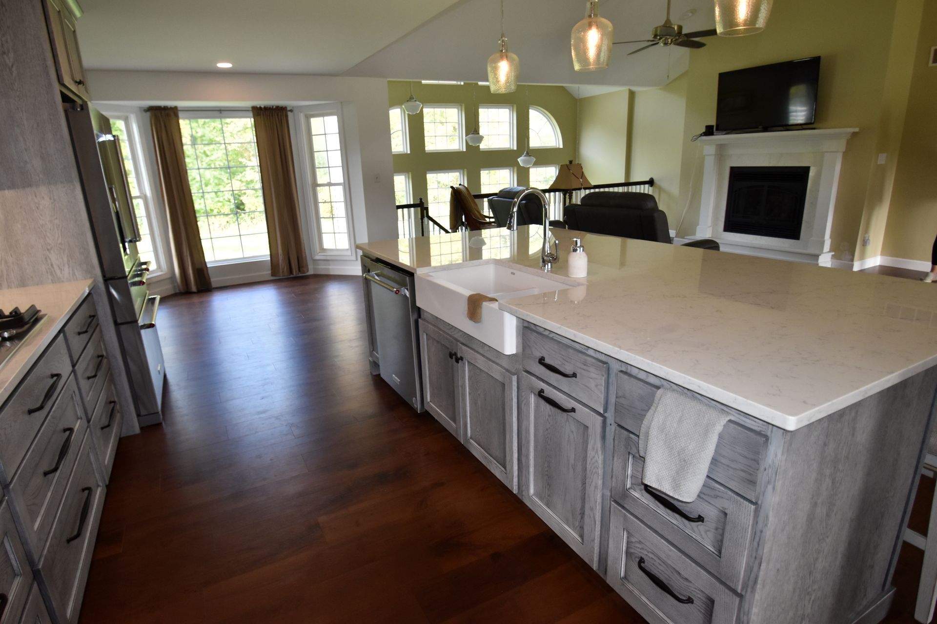 Bright modern kitchen with large island, gray cabinets, hardwood floors, and sliding glass doors to patio.