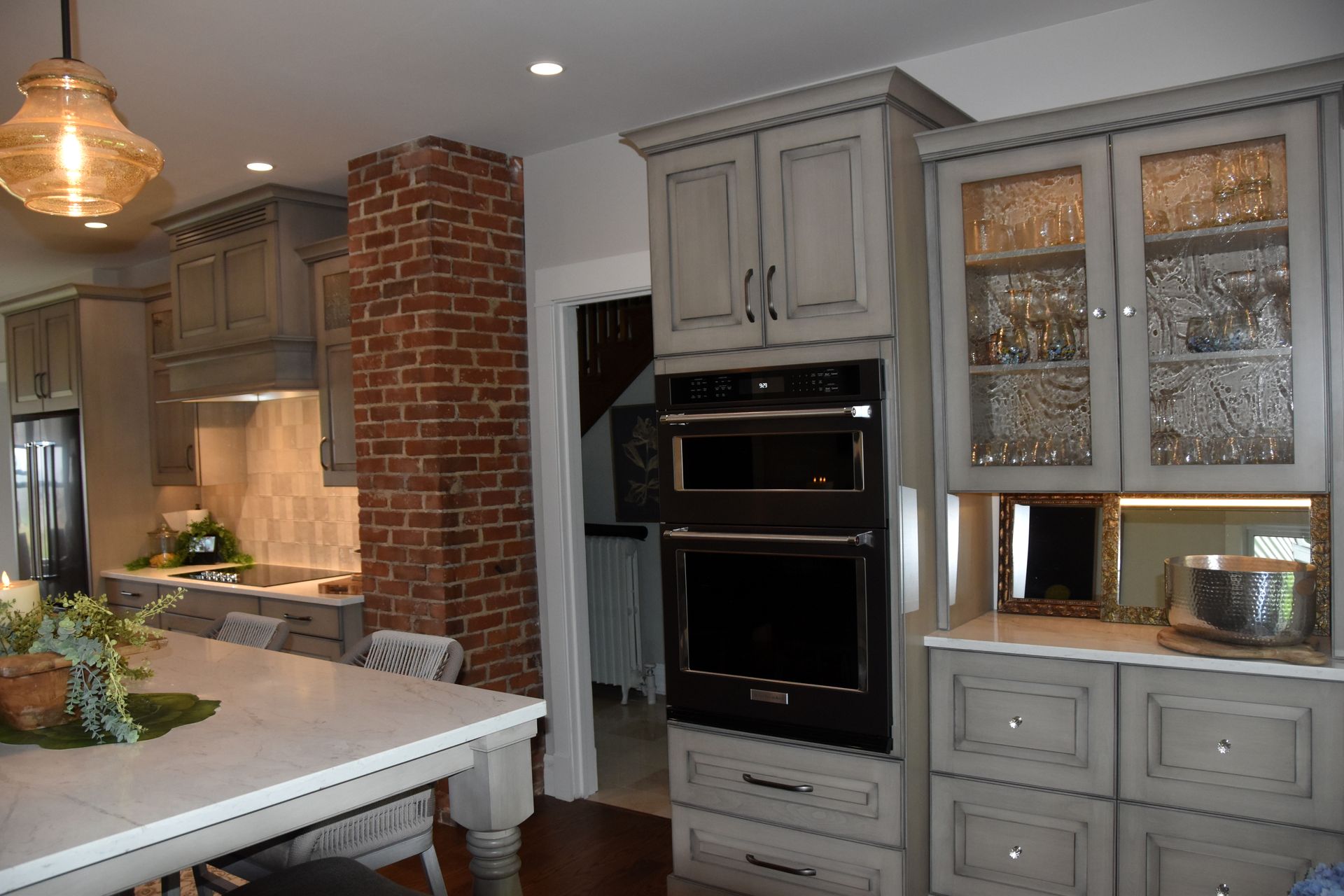 Modern kitchen with gray cabinets, brick accent wall, island, and built-in ovens