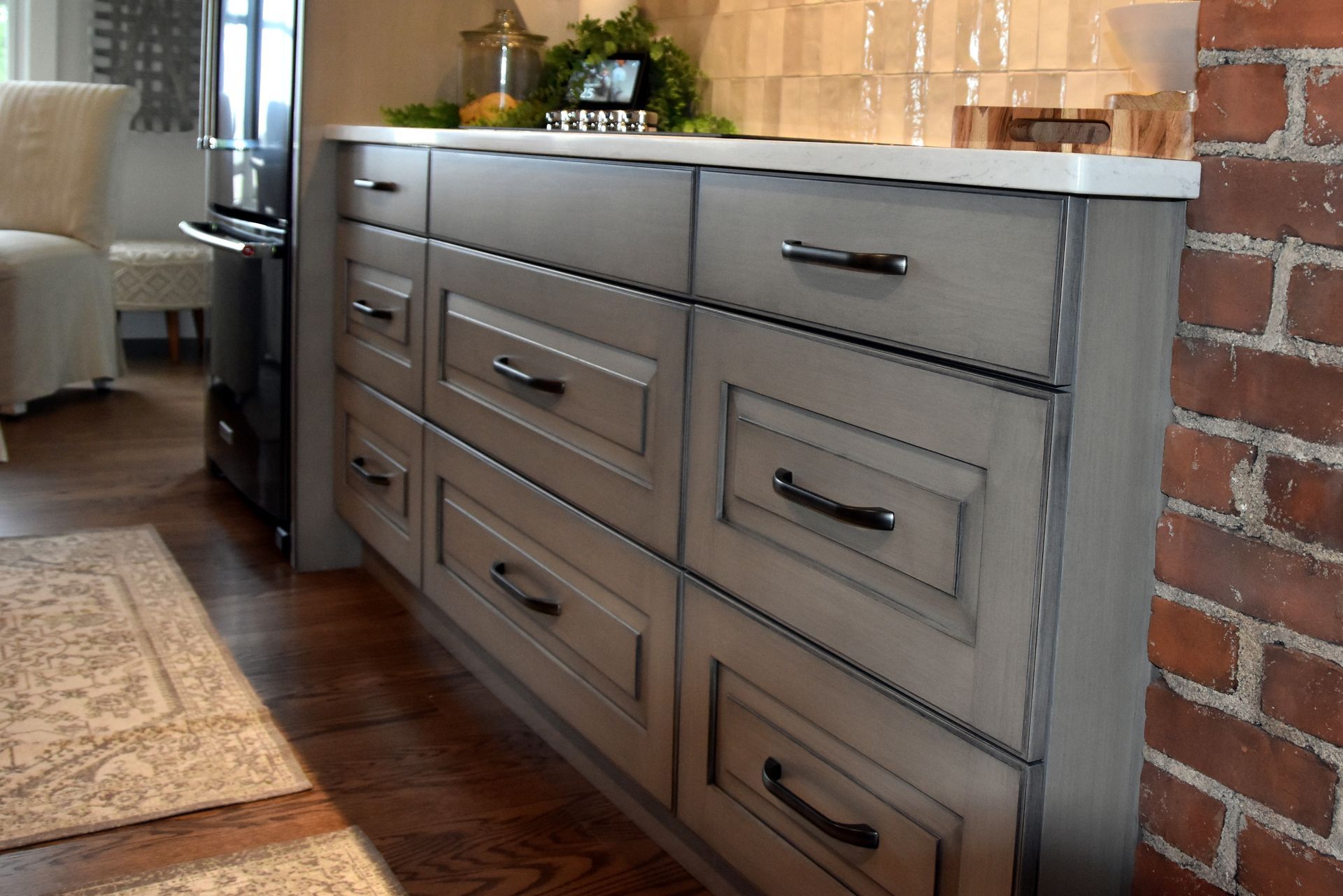 Gray wood sideboard with drawers and black handles against a brick wall in a modern room
