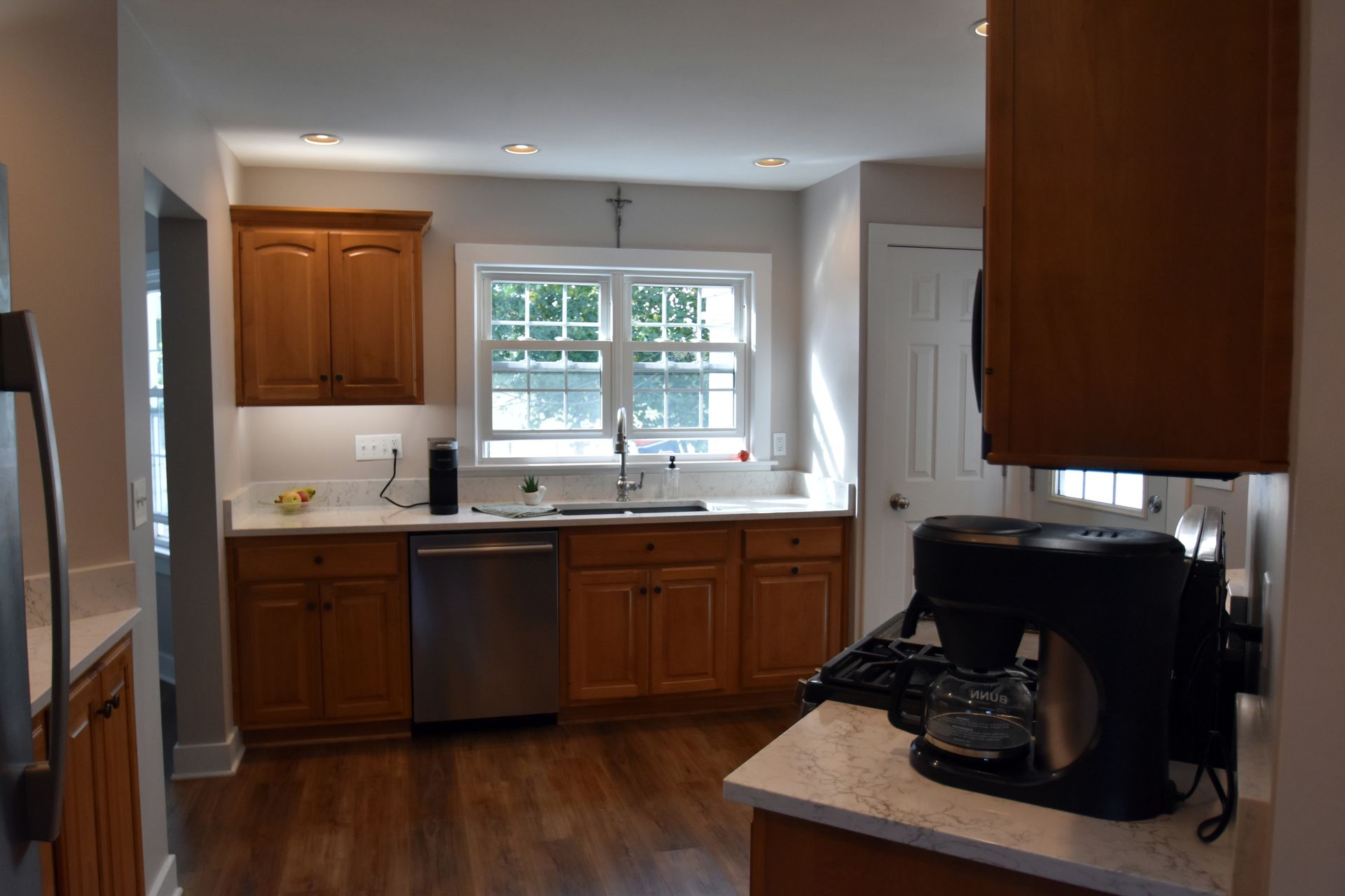 Modern kitchen with wood cabinets, stainless dishwasher, window over sink, and coffee maker on counter