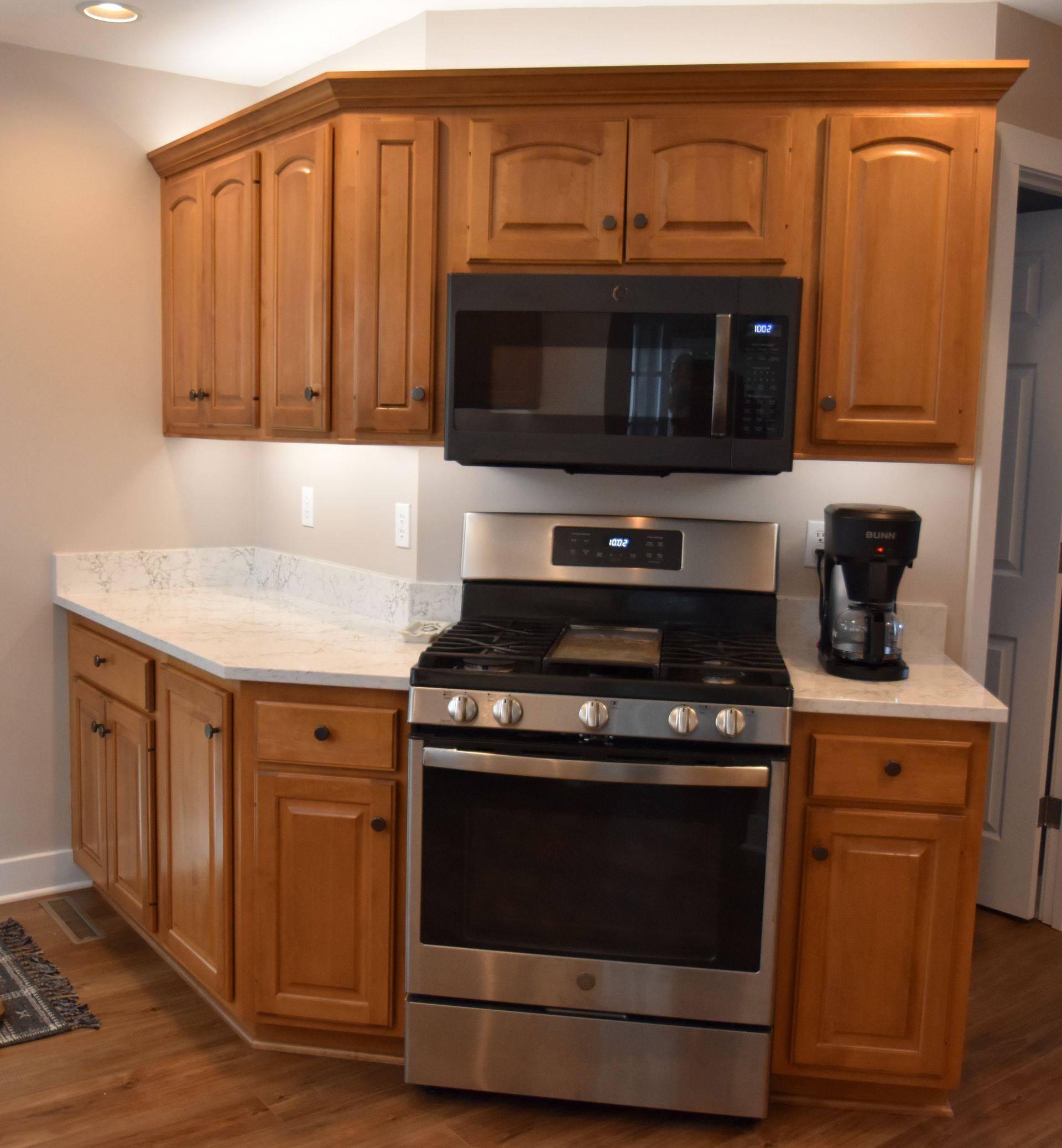 Kitchen with wooden cabinets, stainless steel stove and microwave, granite counters, and a coffee maker.