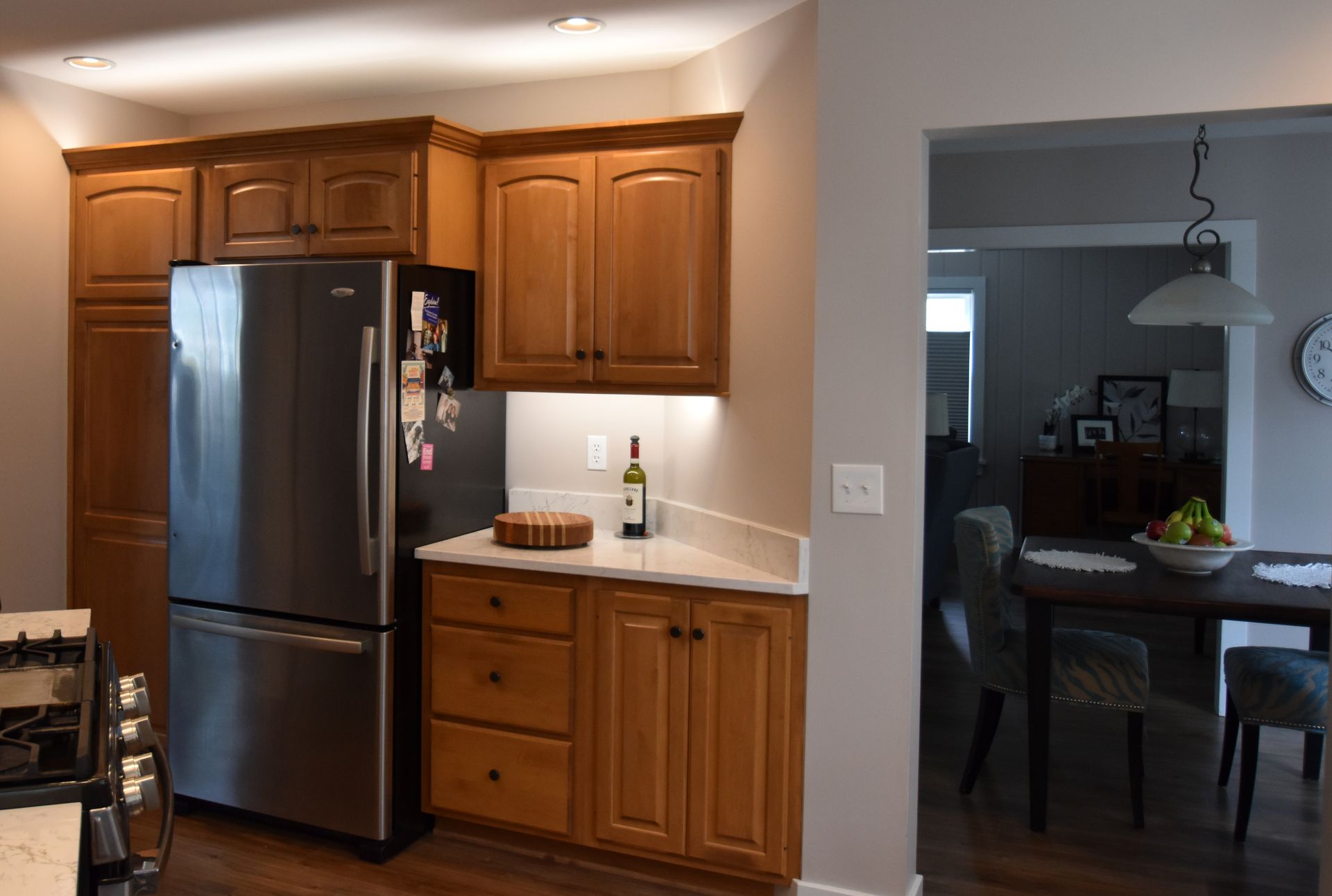 Kitchen with wooden cabinets, stainless steel refrigerator, and doorway to a dining room.