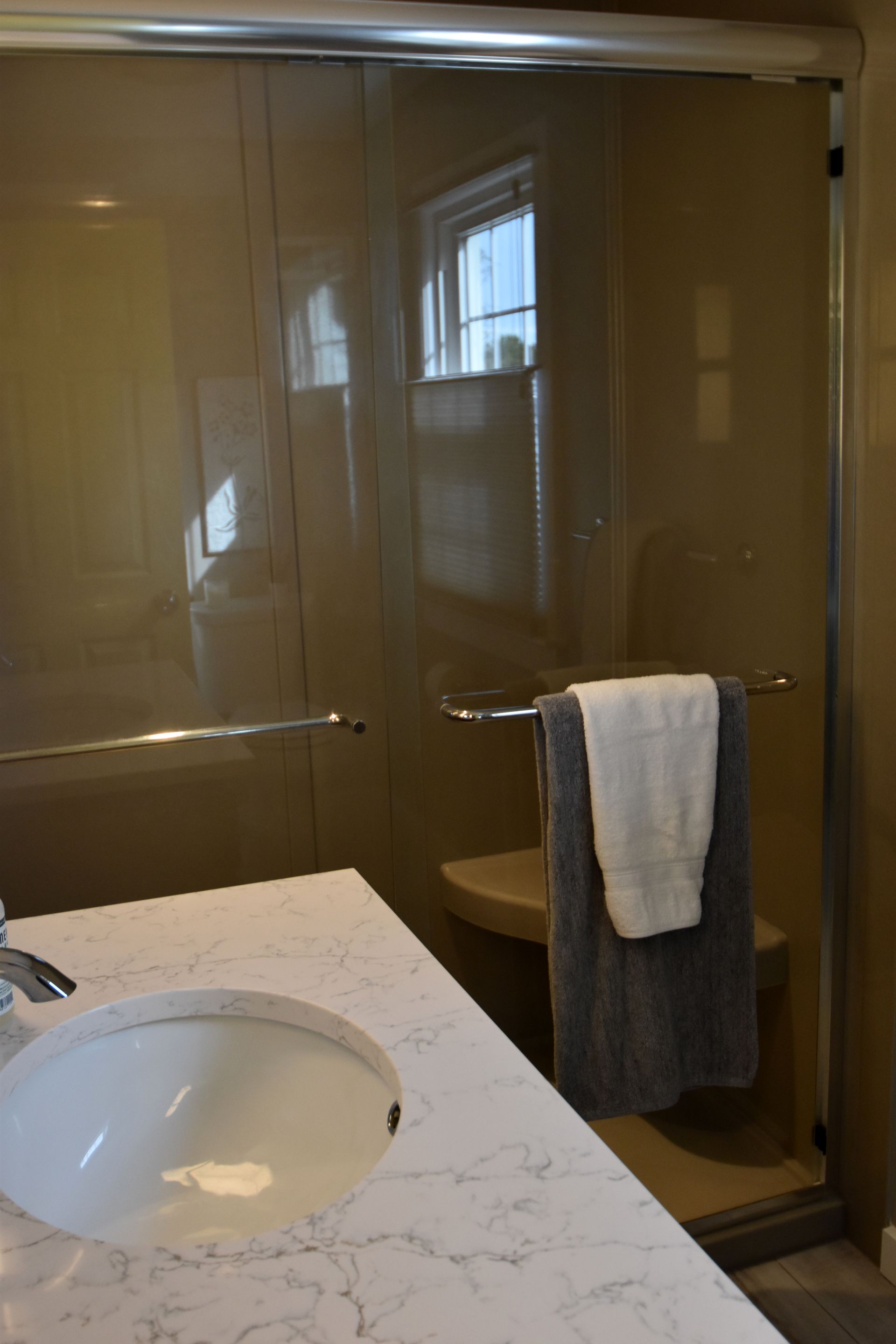 Bathroom vanity and glass shower enclosure with a towel hanging on the shower door.
