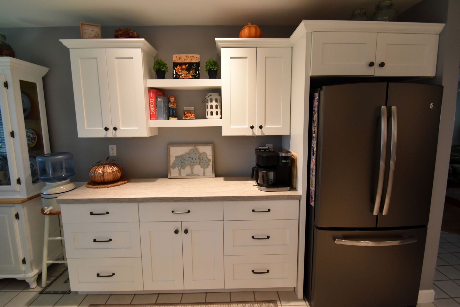 Modern kitchen with white cabinets, dark countertop, and stainless-steel refrigerator and appliances.