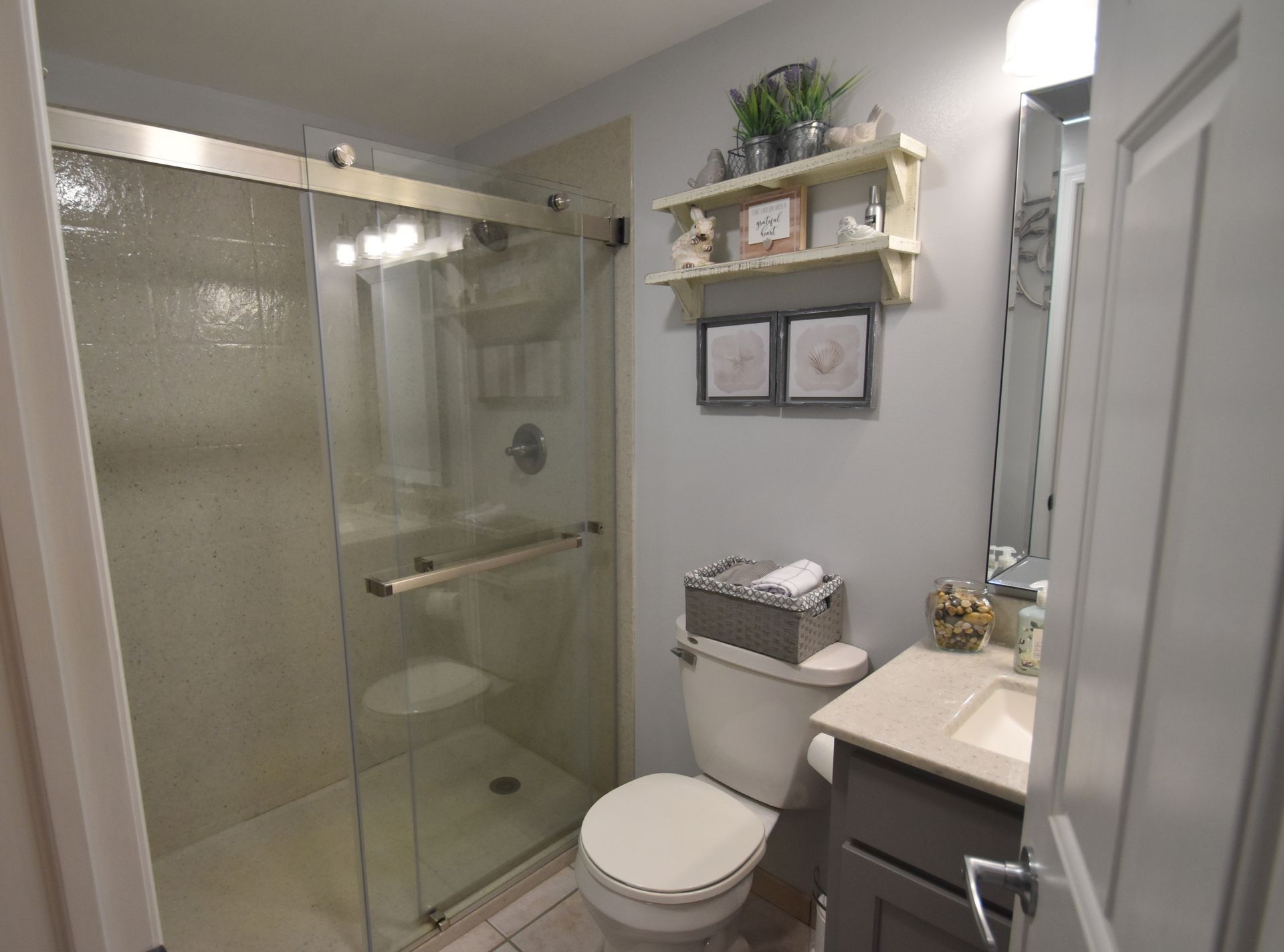 Modern bathroom with glass shower, toilet, vanity, and gray walls