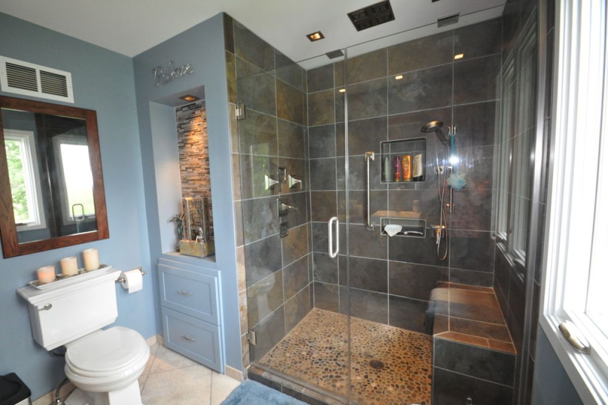 Modern bathroom with glass shower, toilet, and blue-gray walls
