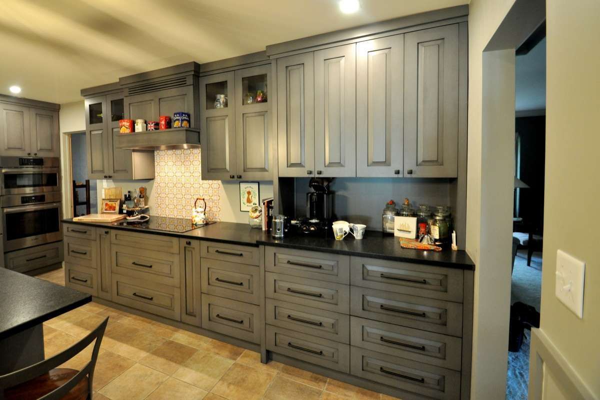 Modern kitchen with gray cabinets, black countertops, and warm lighting
