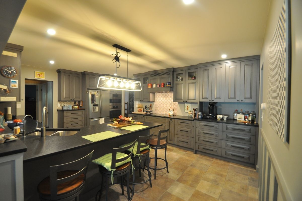Modern gray kitchen with island, pendant light, barstools, and tiled floor