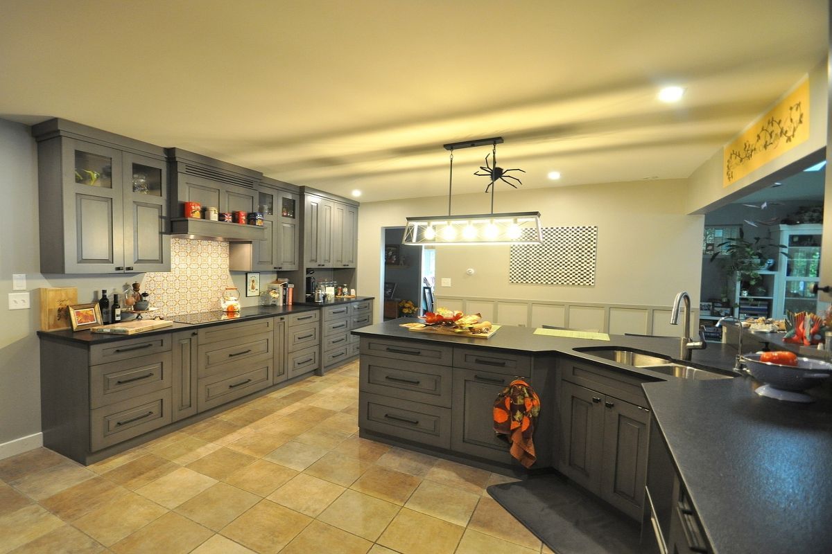 Spacious modern kitchen with gray cabinets, island, tile floor, and countertop decor