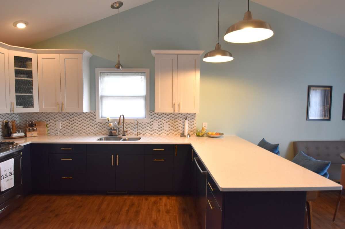 Modern kitchen with dark cabinets, white island countertop, pendant lights, and blue walls
