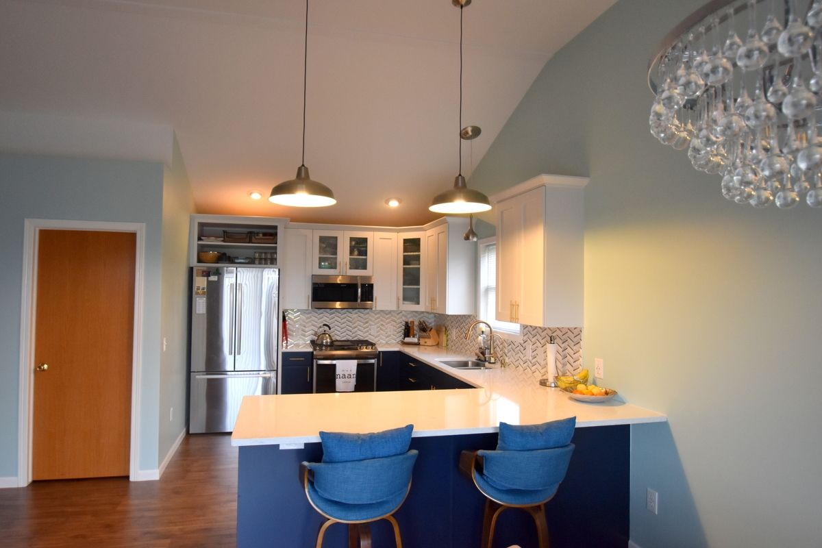 Modern kitchen with blue stools, white island, stainless appliances, and hardwood floors