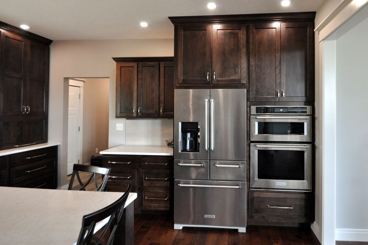 Modern kitchen with dark wood cabinets, stainless steel appliances, and a light countertop
