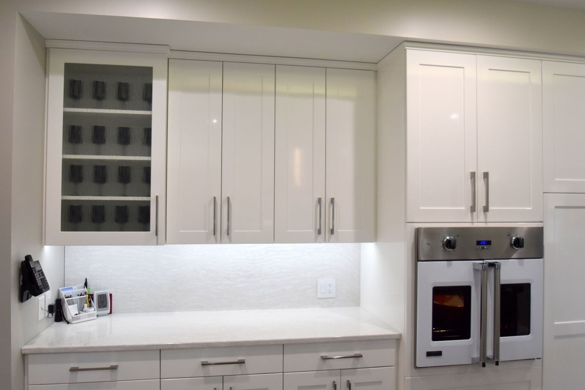 White modern kitchen with cabinets, counter, and built-in double oven and microwave.