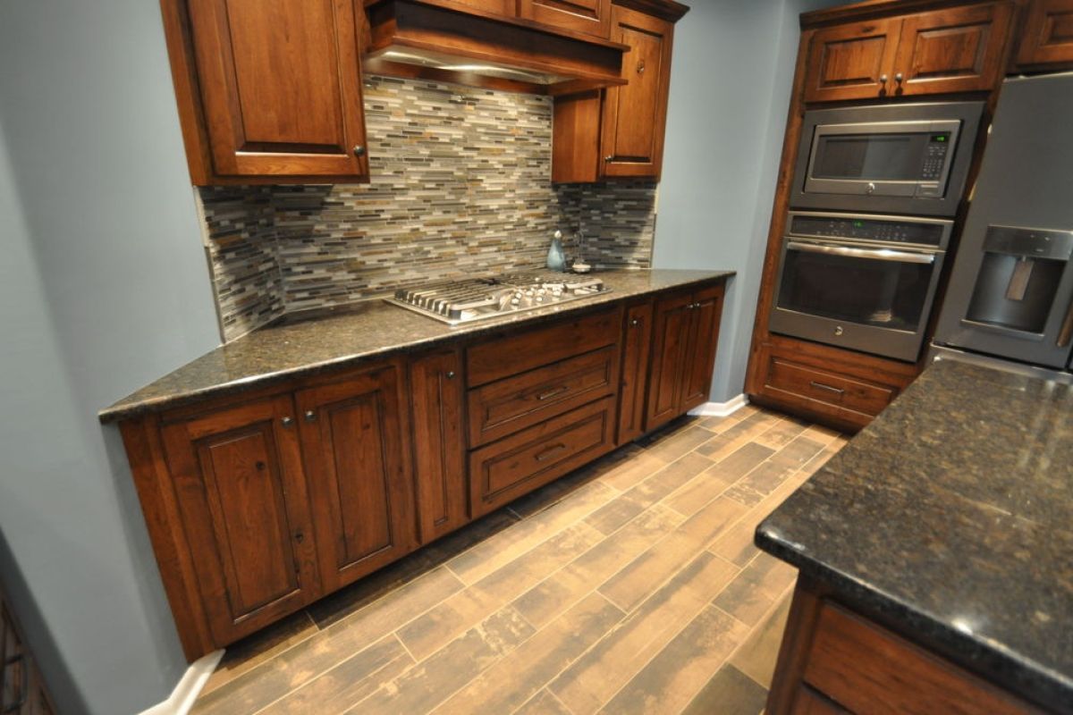 Modern kitchen with dark wood cabinets, stone backsplash, and black countertops