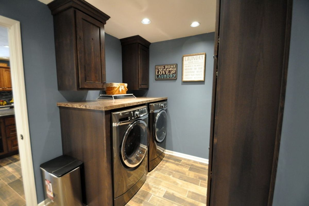 Laundry room with front-loading washer and dryer, dark wood cabinets, and gray walls
