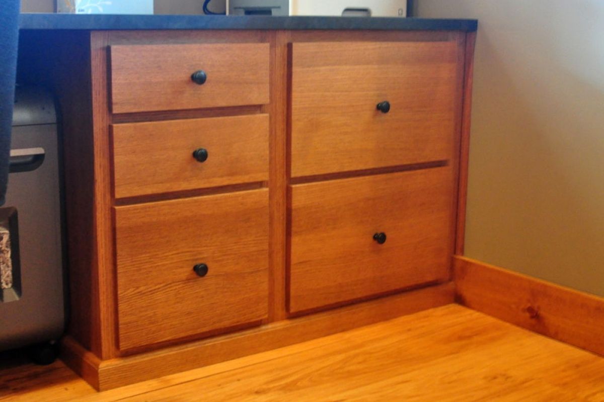 Wooden dresser with four drawers beside a wall on a hardwood floor.